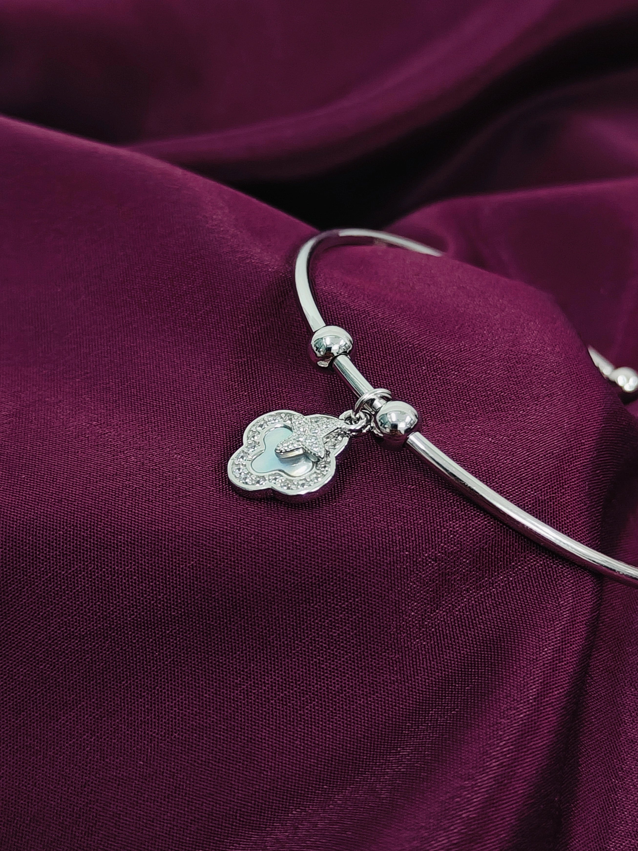 Silver bracelet with a heart-shaped charm on a purple fabric background