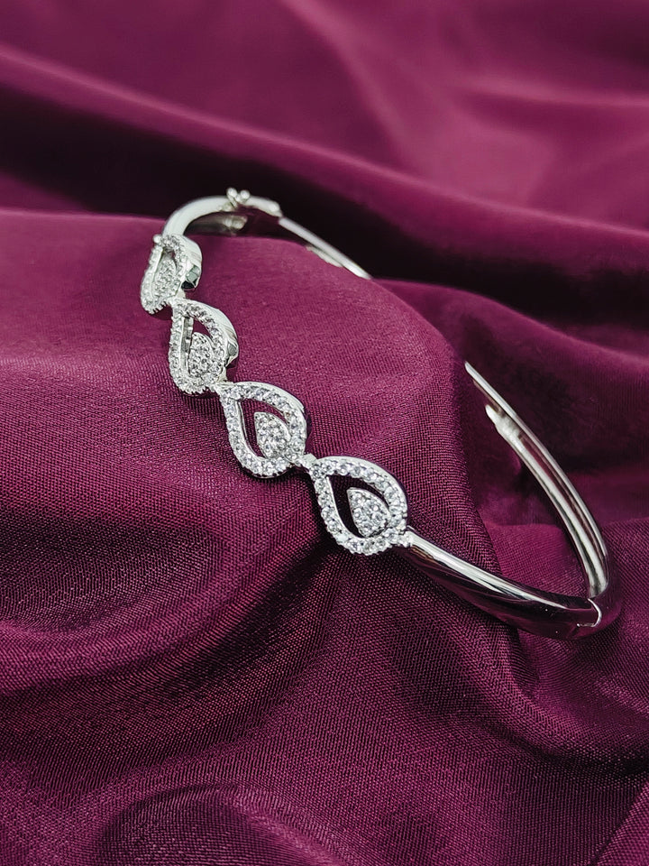Silver bracelet with diamond-like stones on a purple fabric background