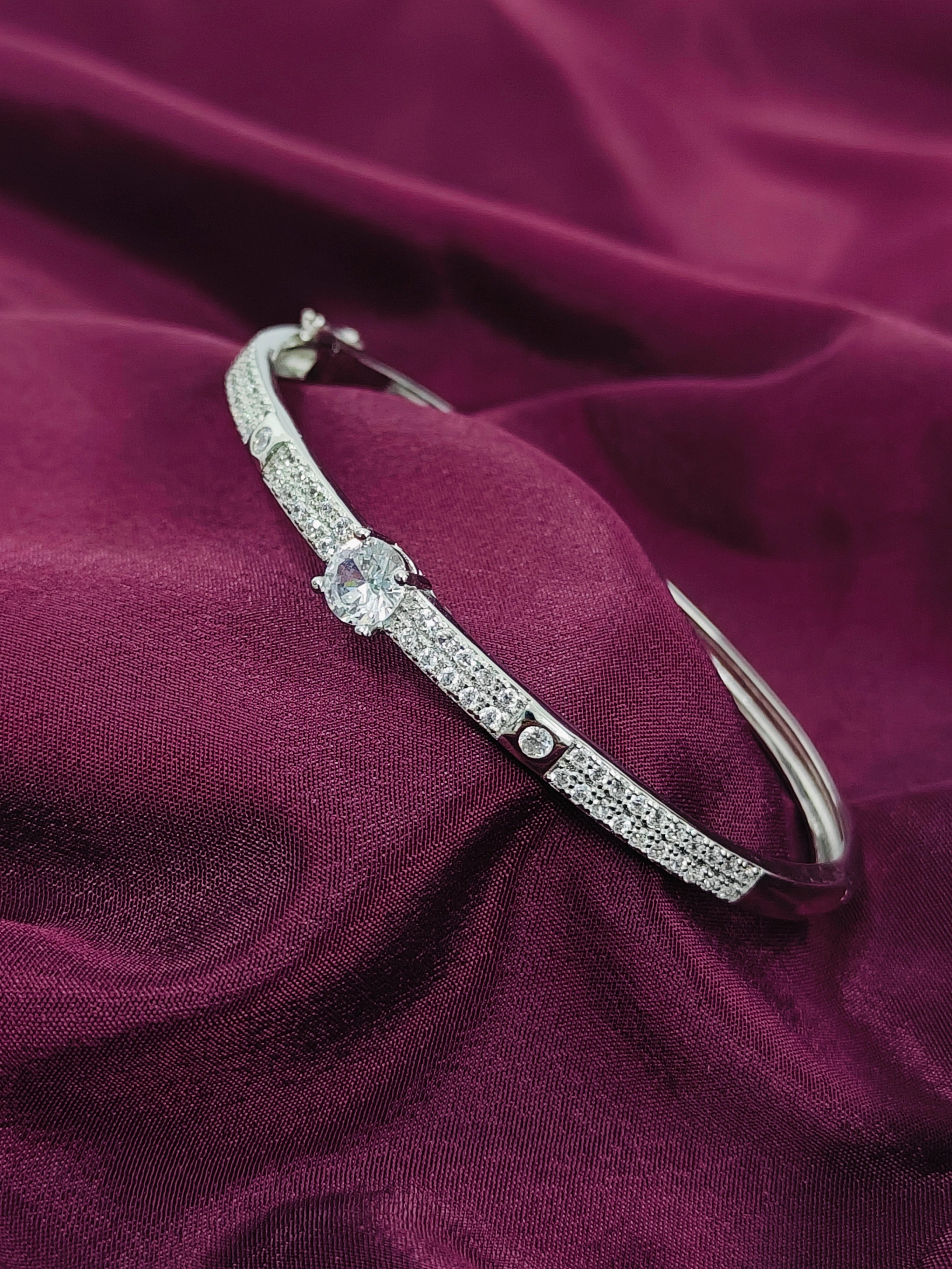 Silver bracelet with floral design on a purple fabric background