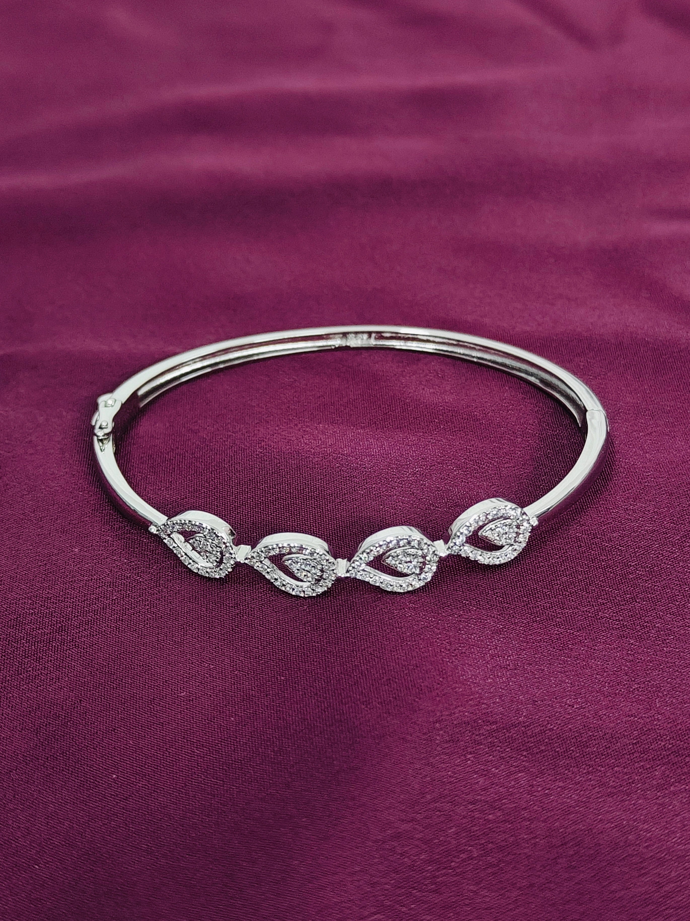 Silver bracelet with intricate design on a purple fabric background