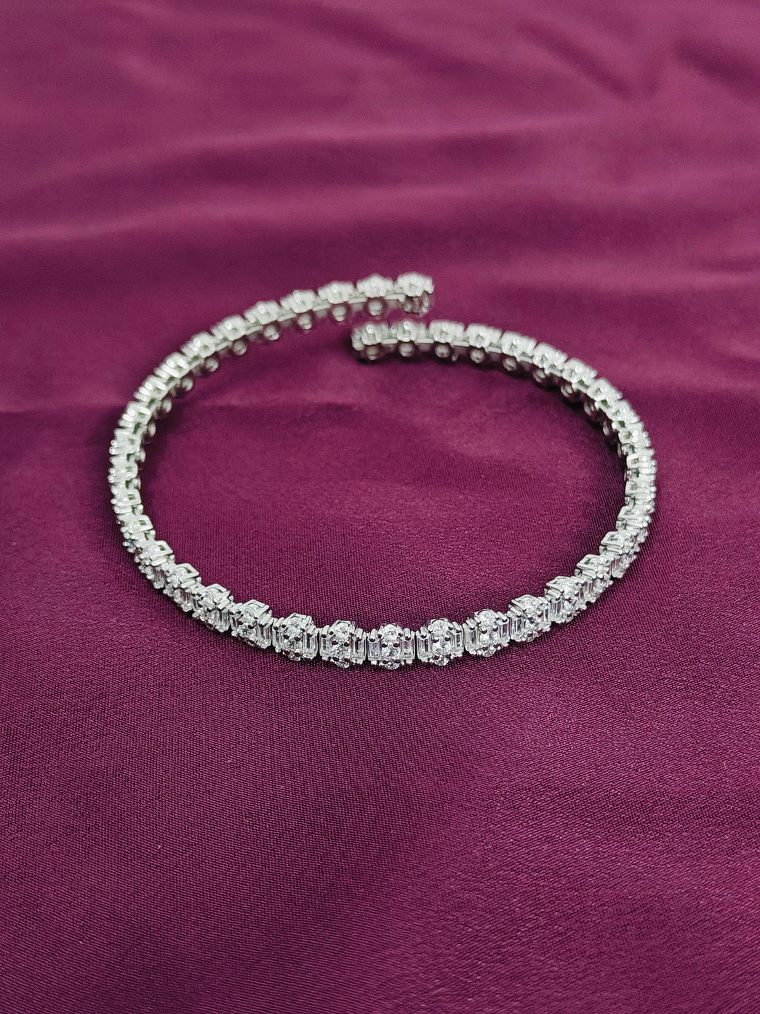 Silver bracelet with clear stones on a purple fabric background