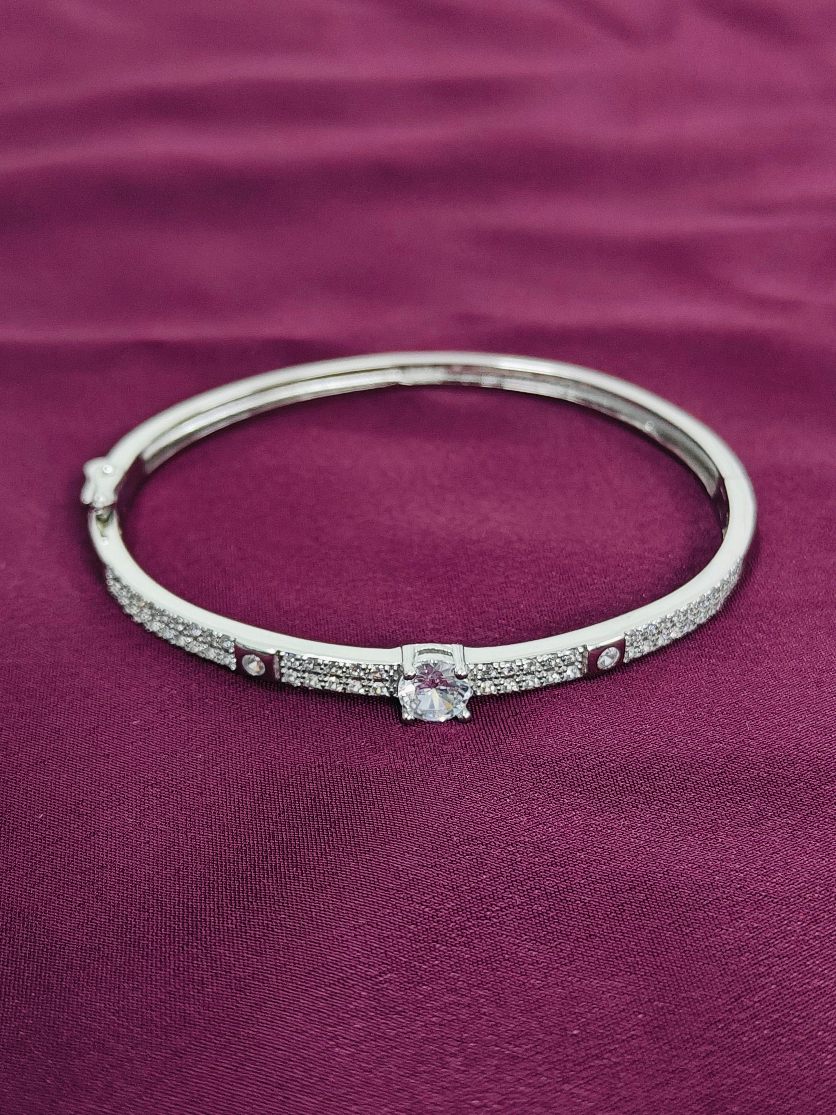 Silver bracelet with a central gemstone on a purple fabric background