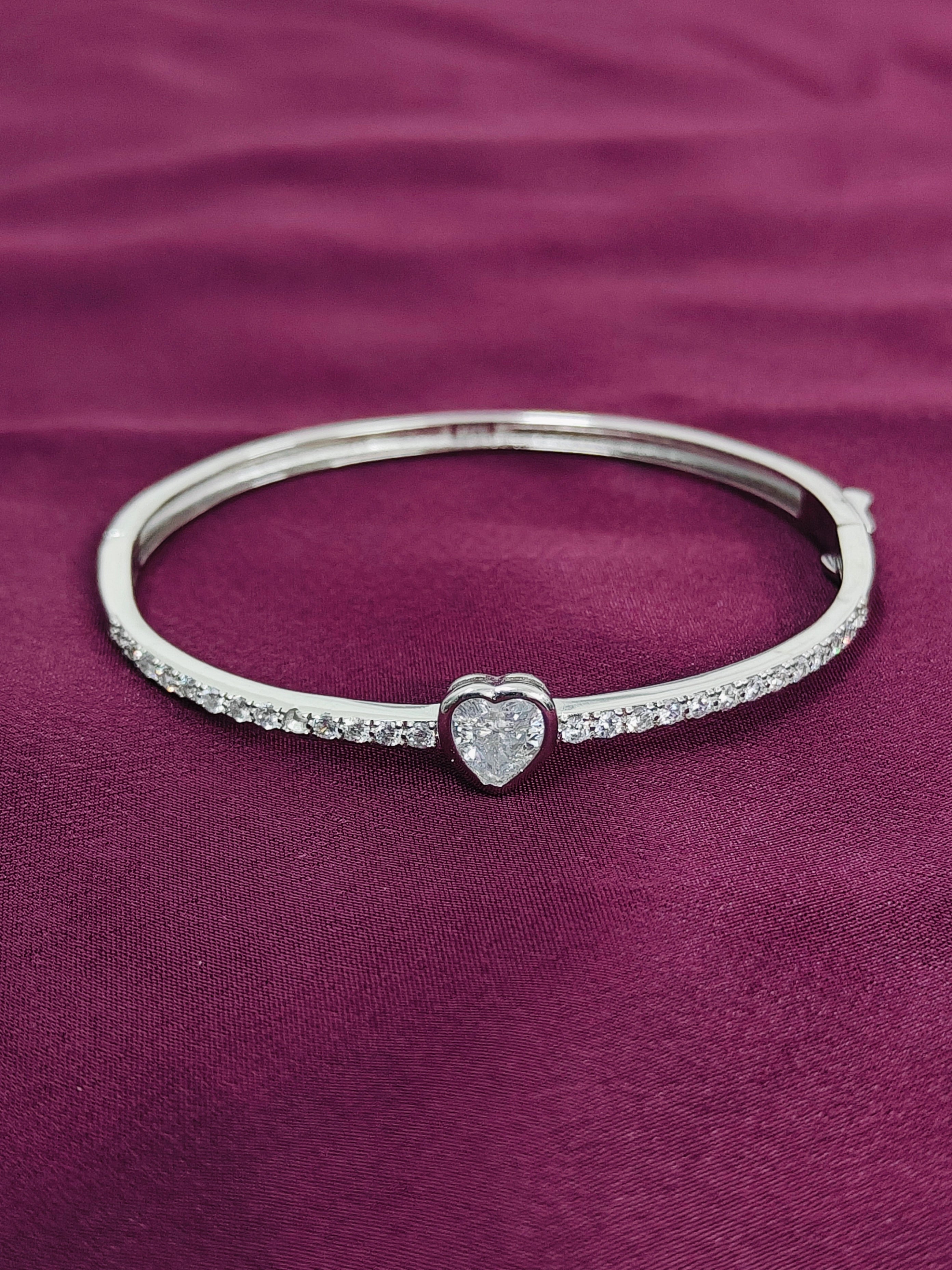 Silver bracelet with a heart-shaped clasp on a purple fabric background