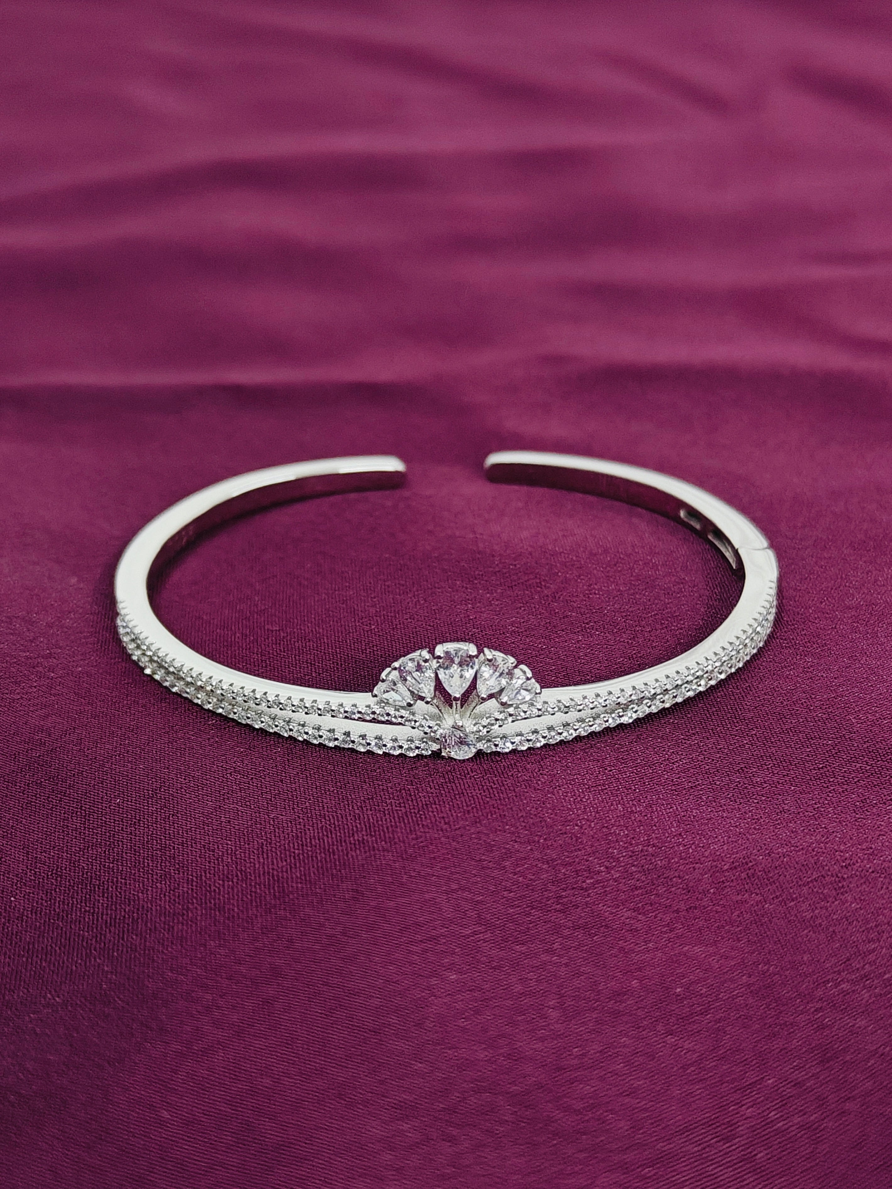 Silver bracelet with a central gemstone on a purple fabric background