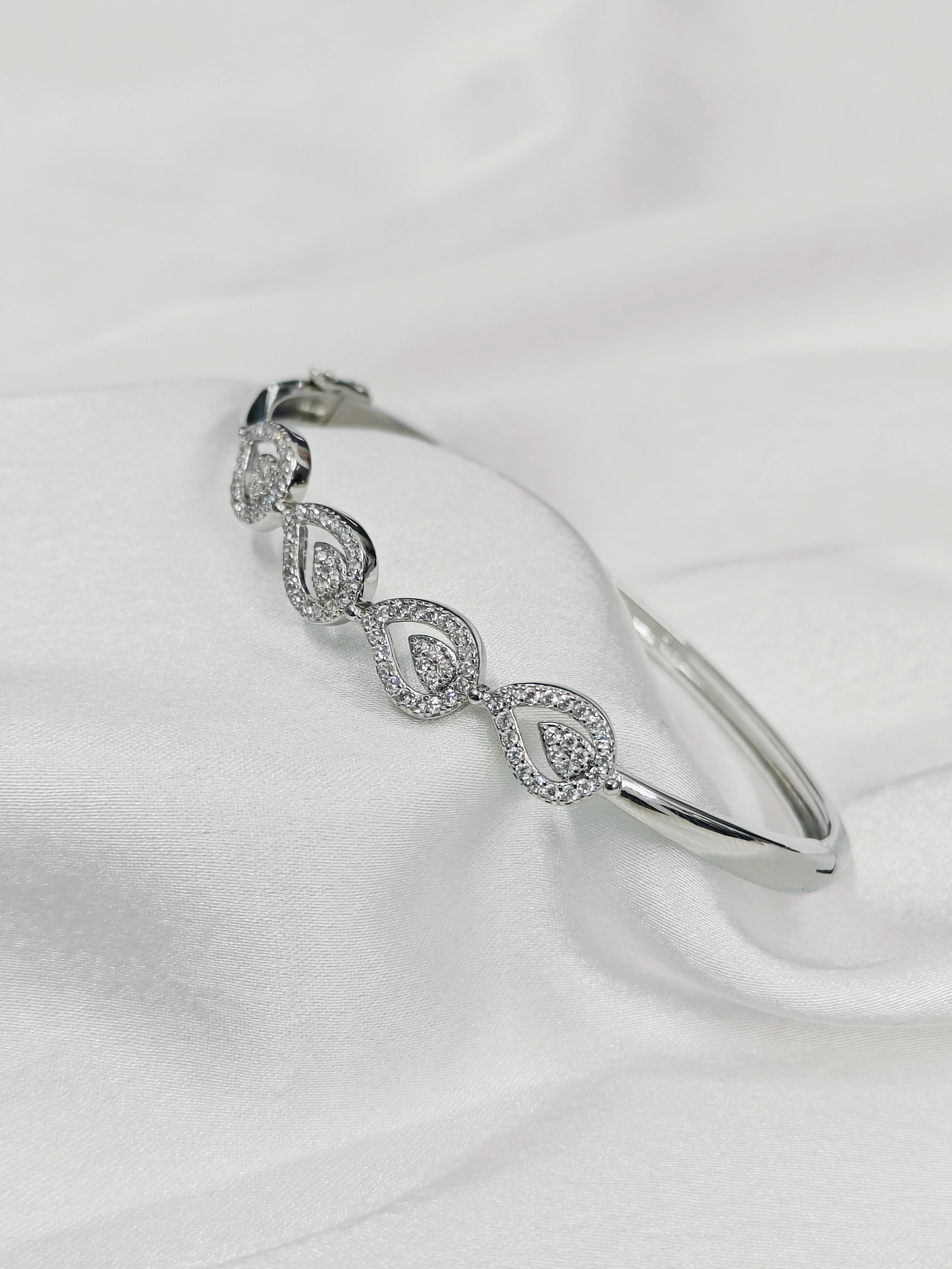 Silver bracelet with diamond accents on a white fabric background