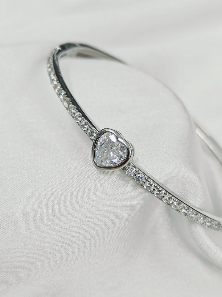 Silver bracelet with a heart-shaped diamond on a light gray background