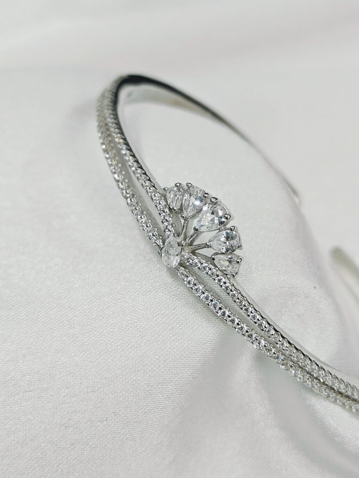 Silver bracelet with a central diamond on a light gray background