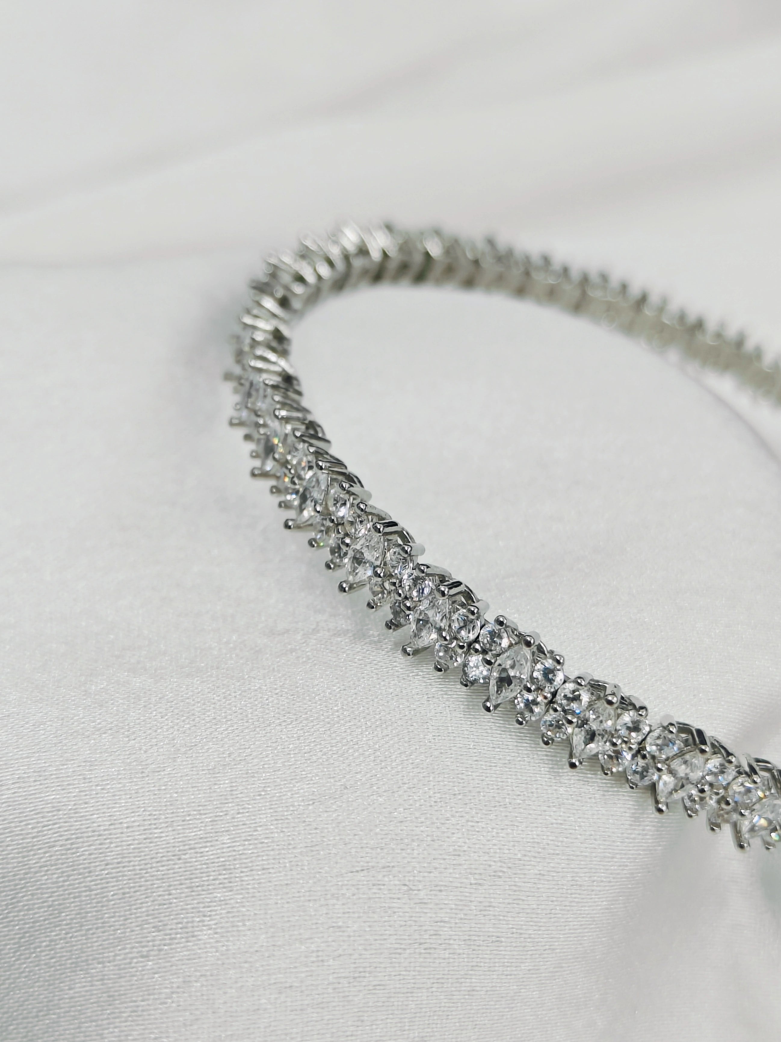 Silver bracelet with clear stones on a light gray background