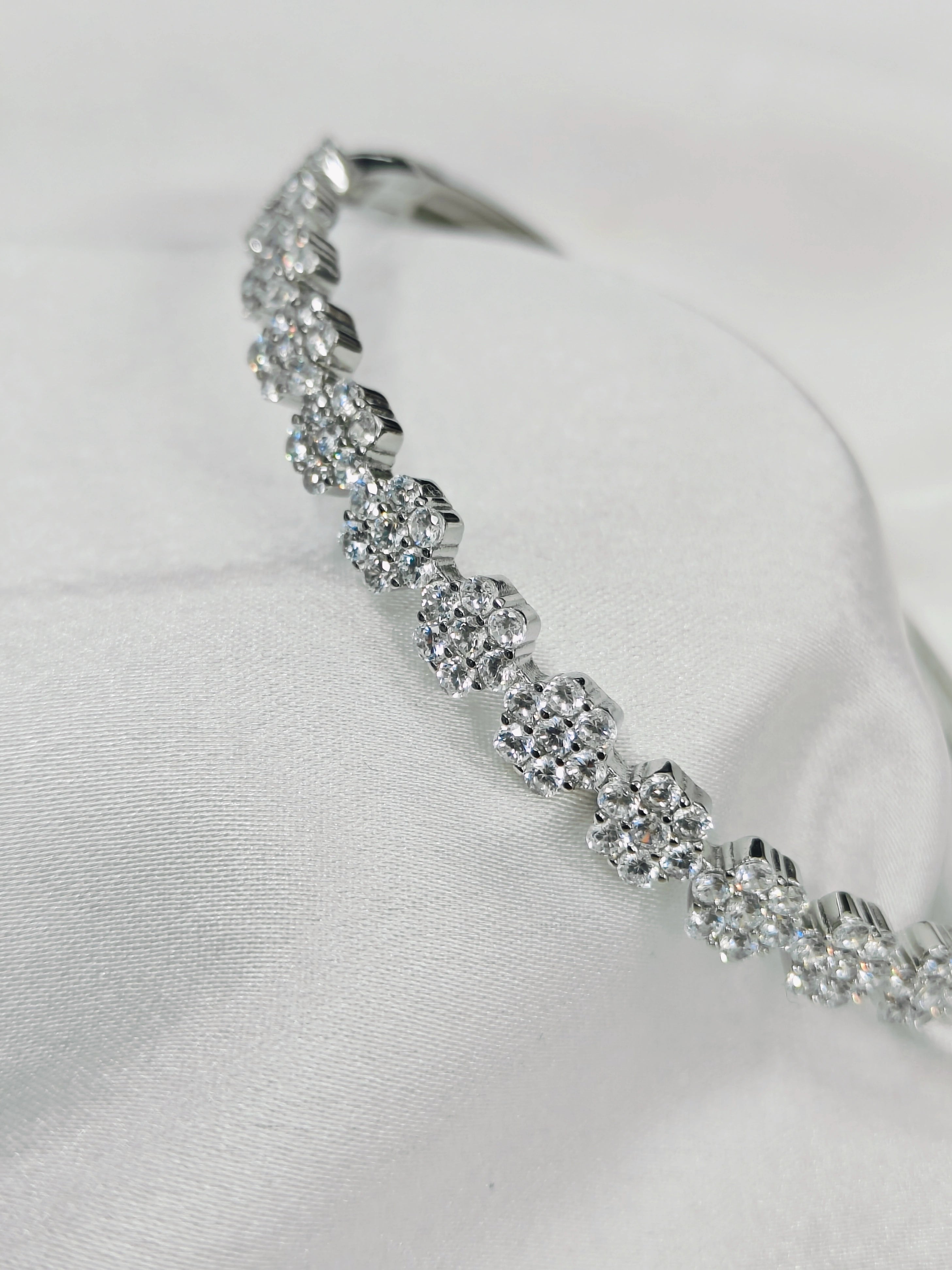 Silver bracelet with clear stones on a white fabric background