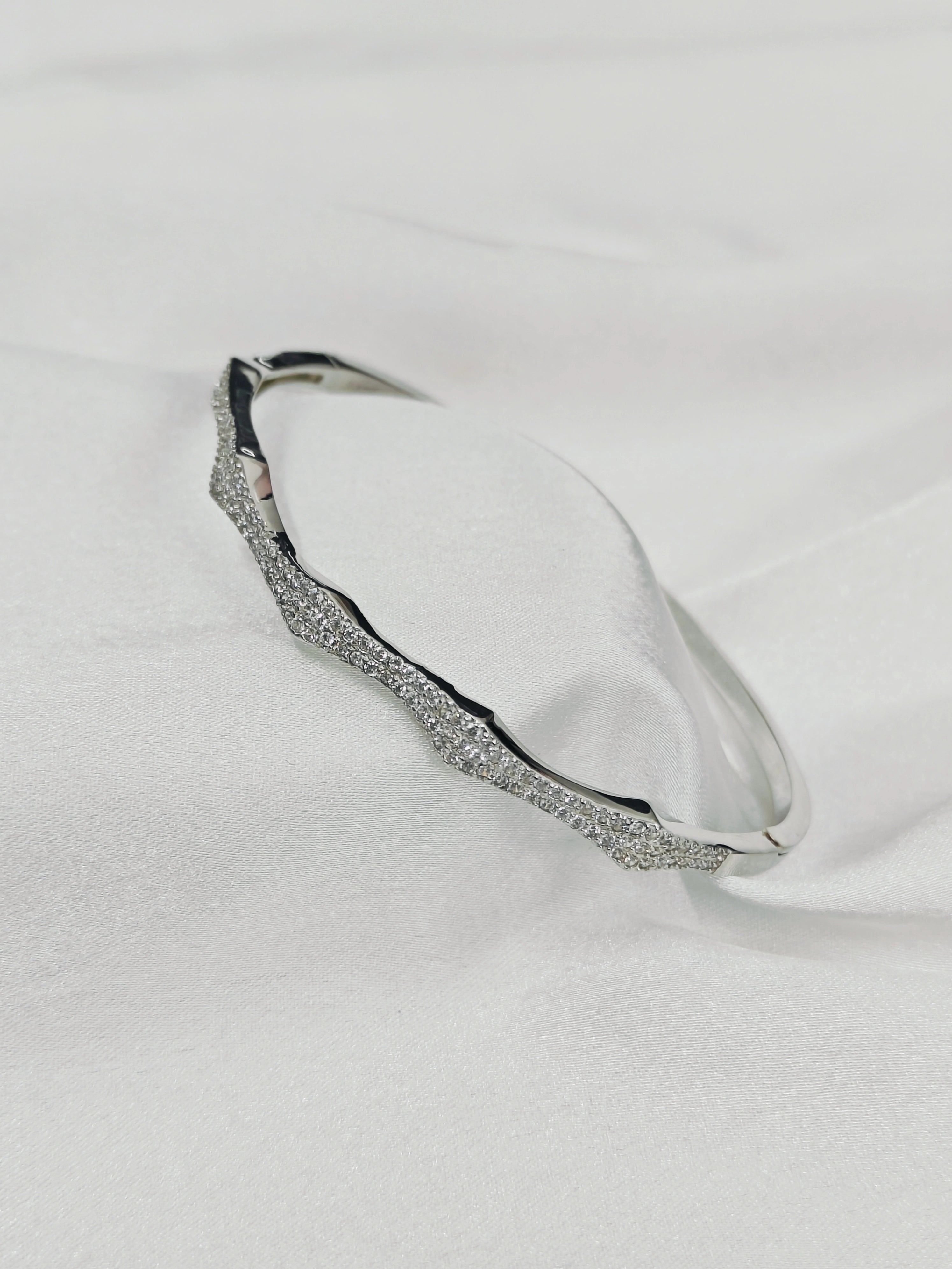 Silver bracelet with small stones on a light gray background