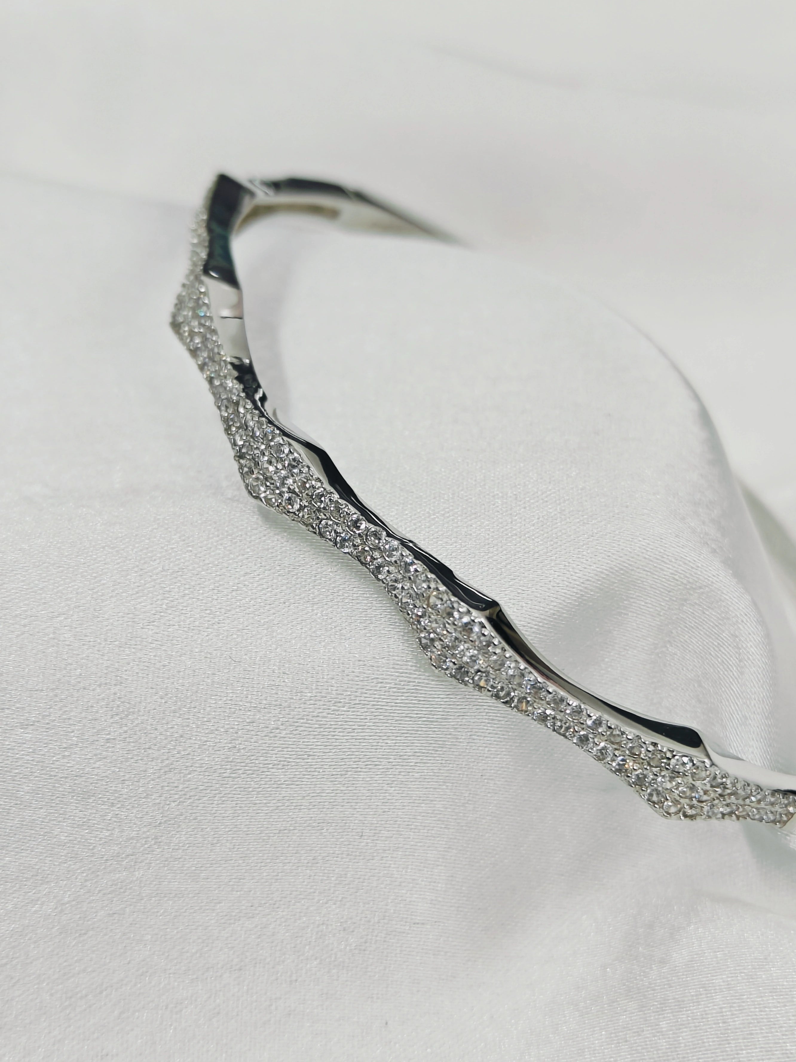 Silver bracelet with clear stones on a white fabric background