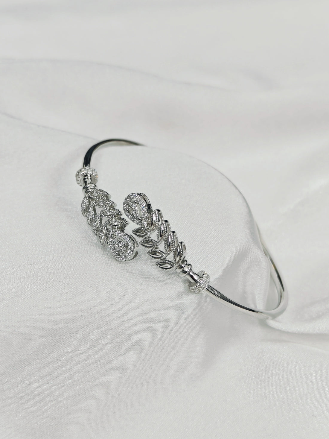 Silver bracelet with floral design on a white background