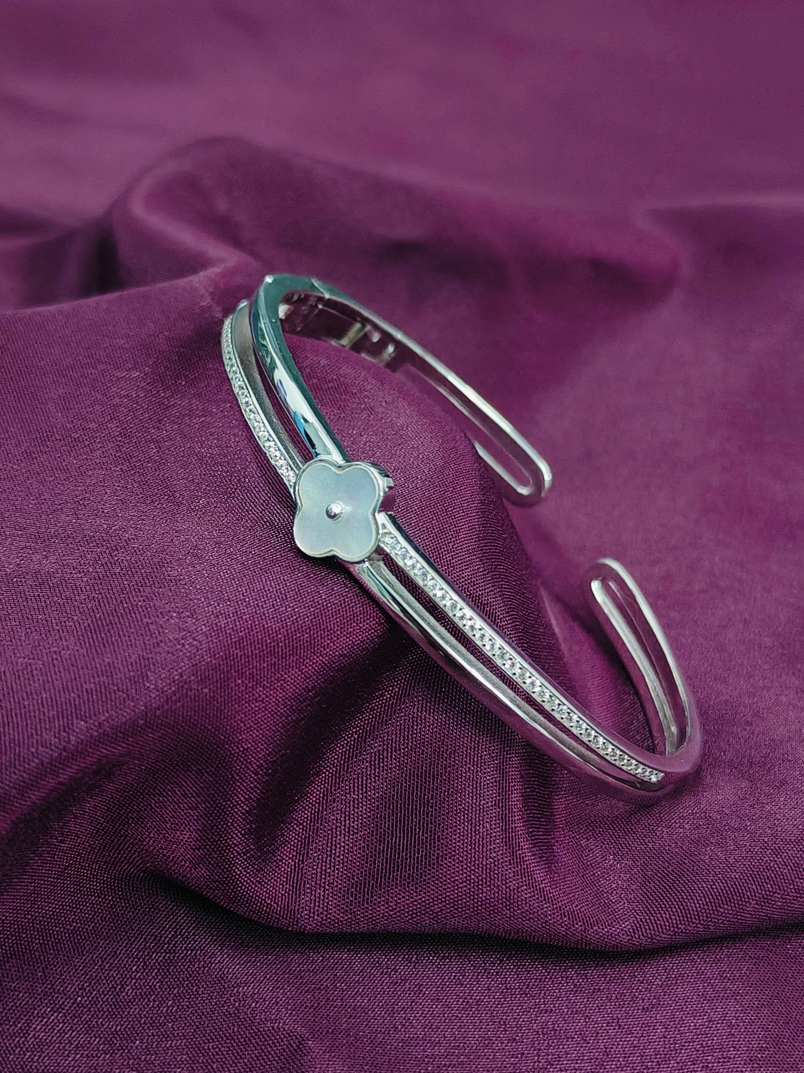 Silver bracelet with a star-shaped clasp on a purple fabric background