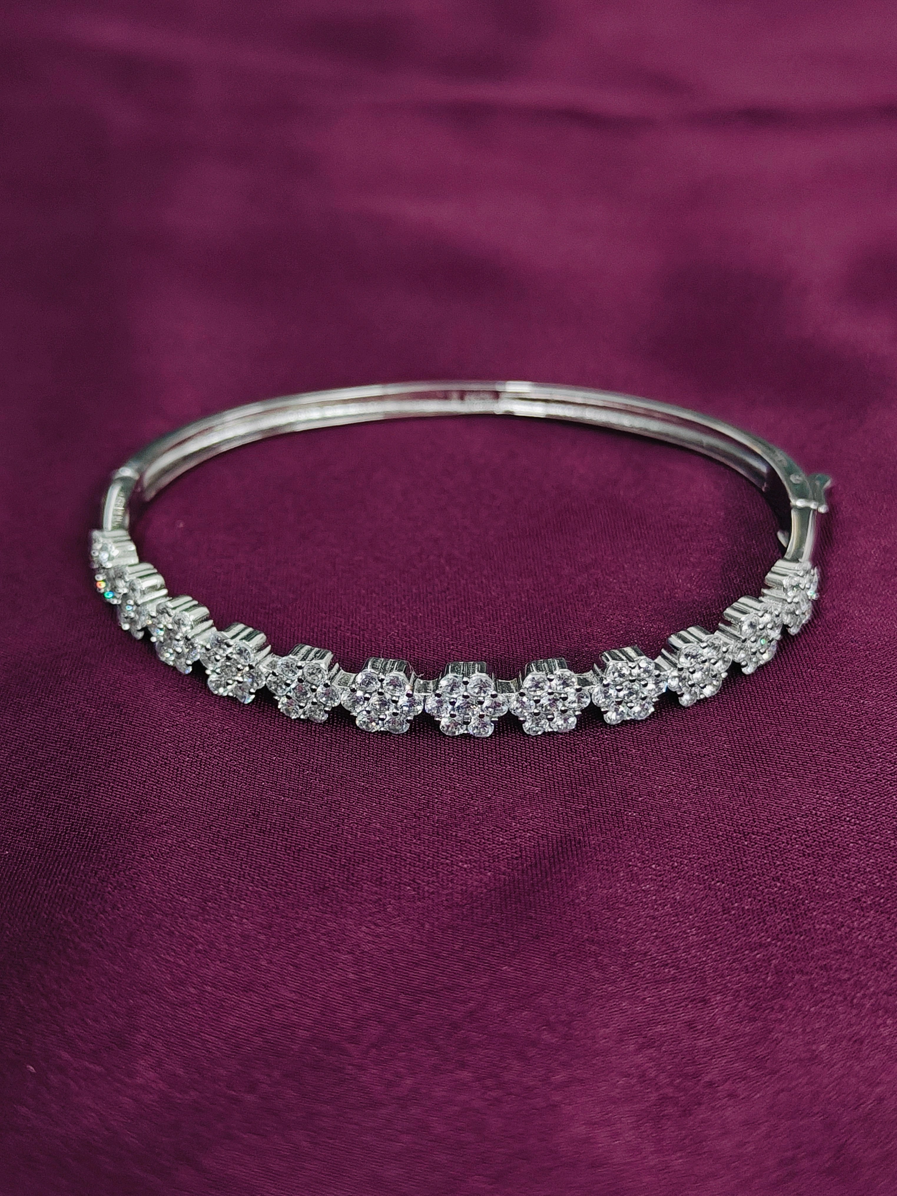 Silver bracelet with floral design on a purple fabric background