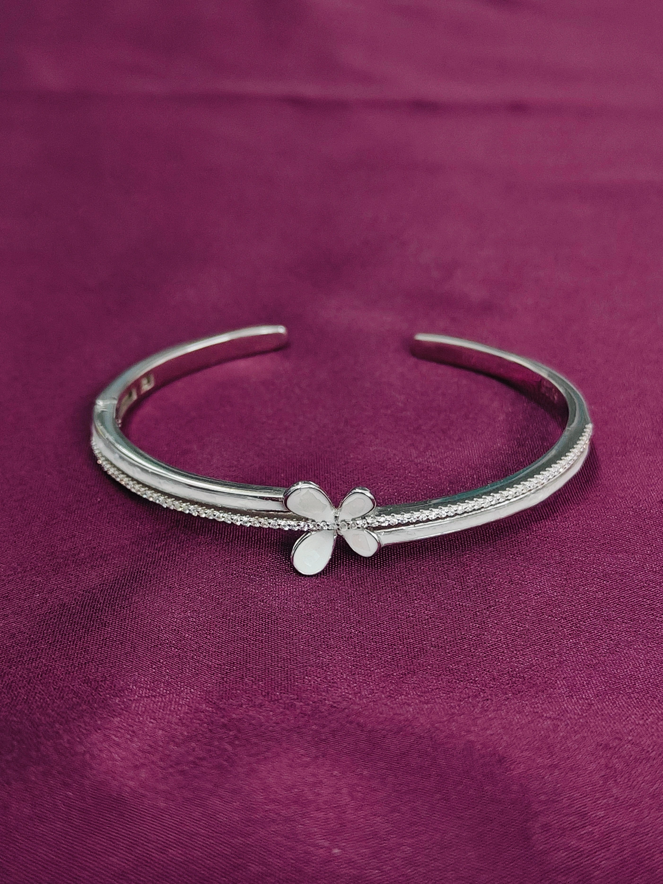 Silver bracelet with a butterfly charm on a purple fabric background
