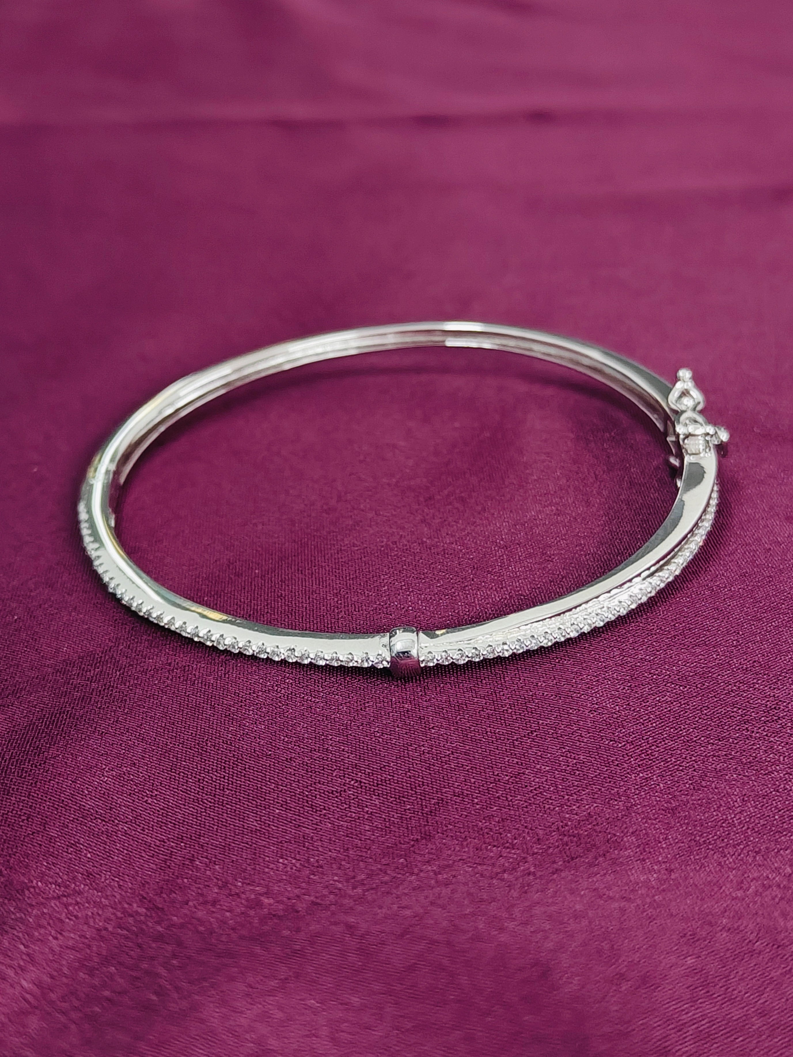Silver bracelet with small diamonds on a purple fabric background