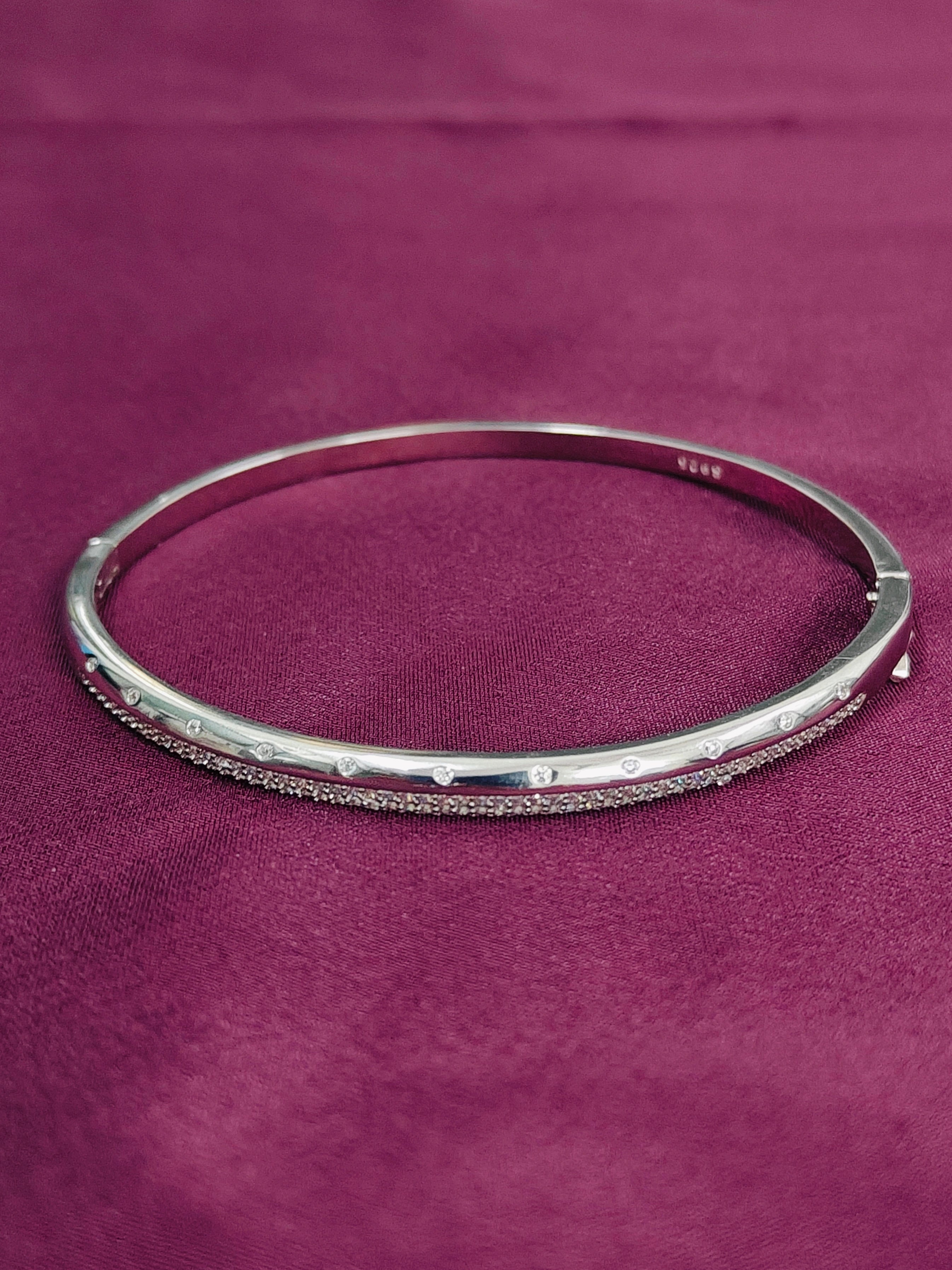 Silver bangle on a purple fabric background