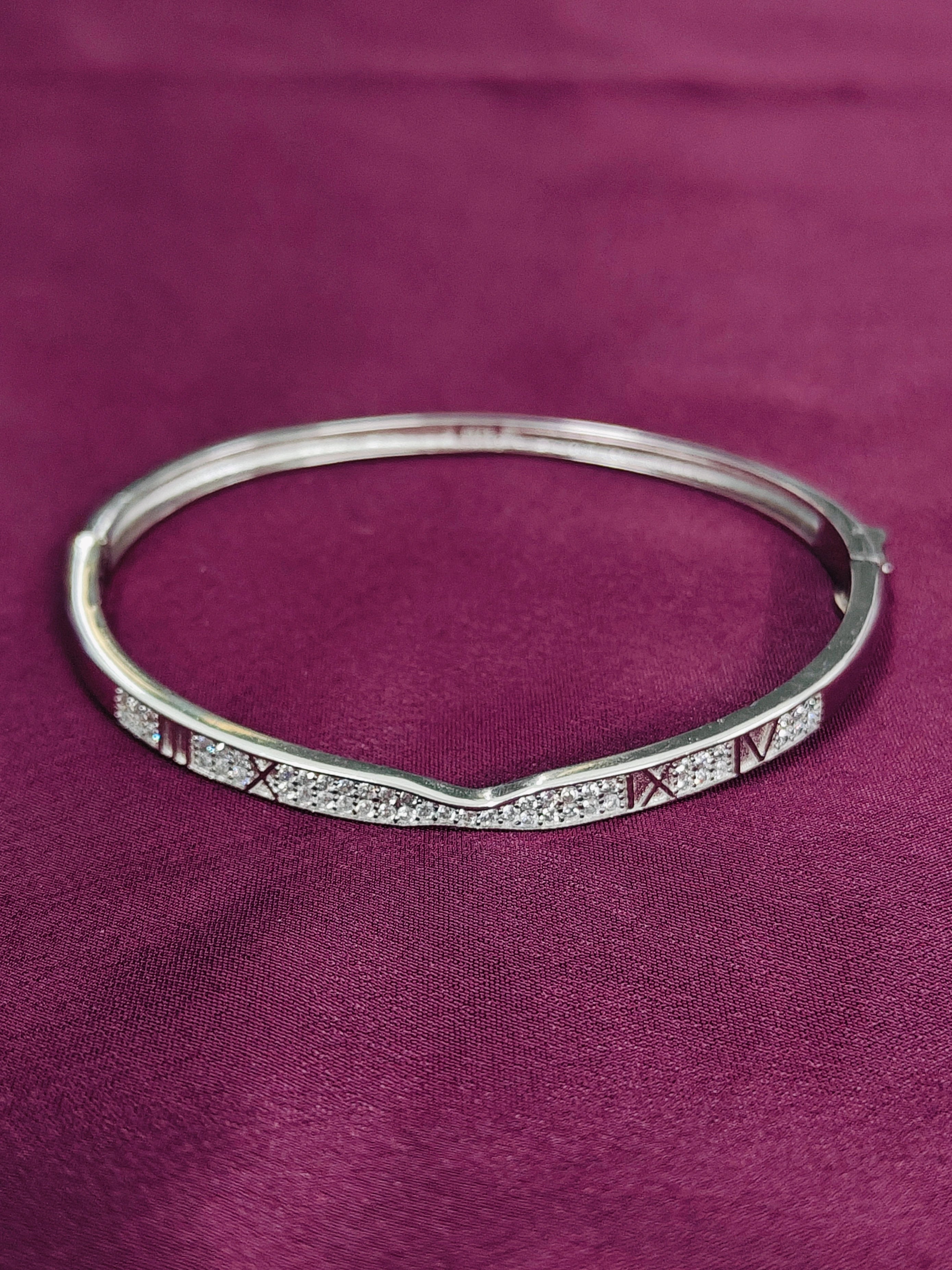 Silver bracelet with red and white stones on a purple fabric background