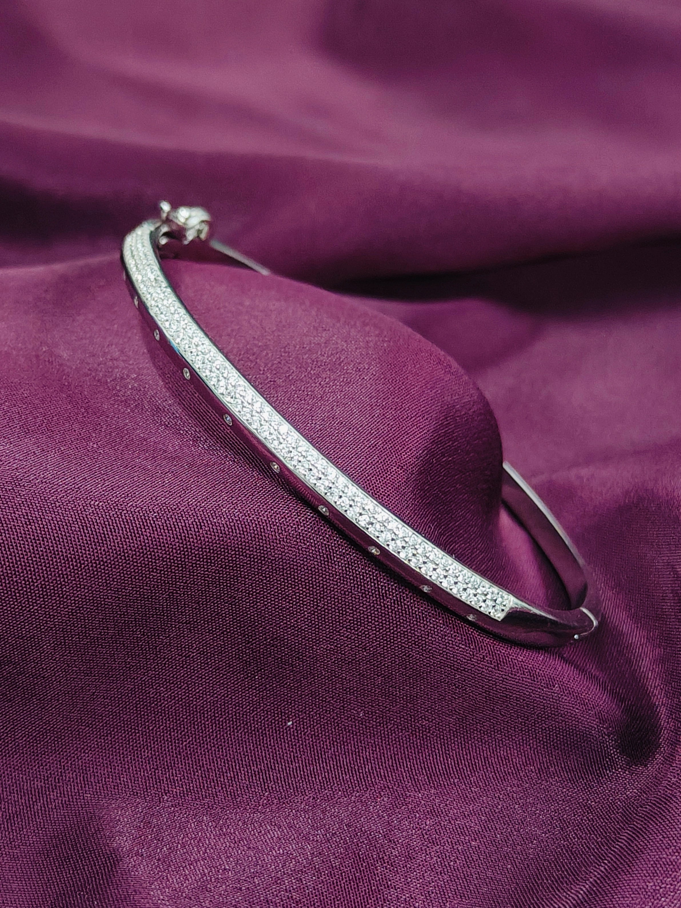 Silver bracelet with small stones on a purple fabric background