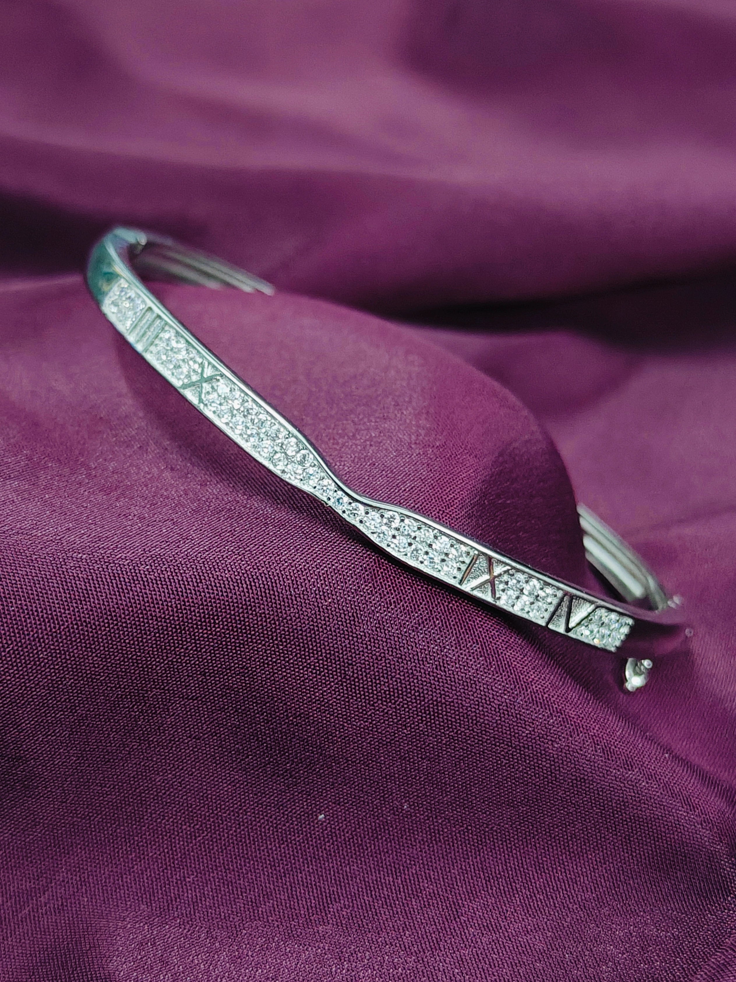 Silver bracelet with gemstones on a purple fabric background