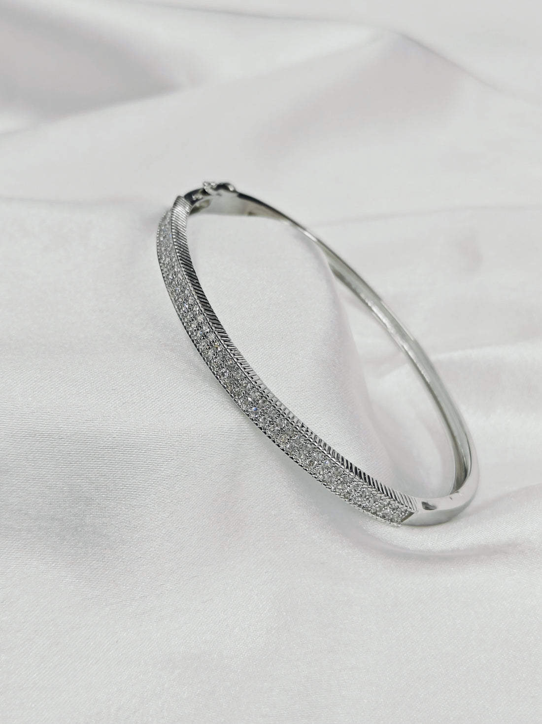 Silver bracelet with small stones on a white fabric background