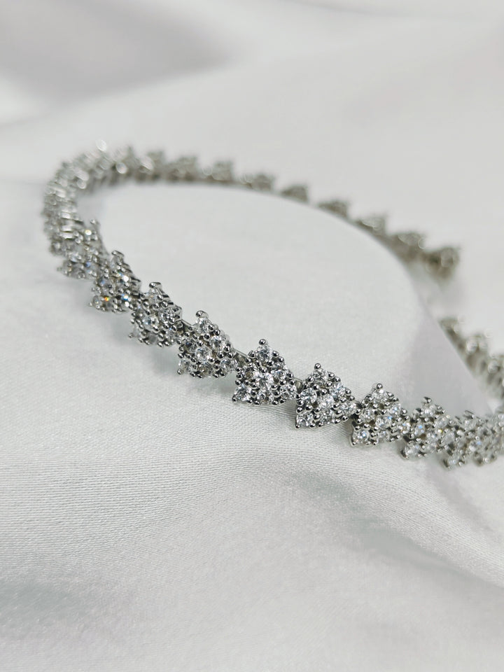 Silver bracelet with clear stones on a white fabric background