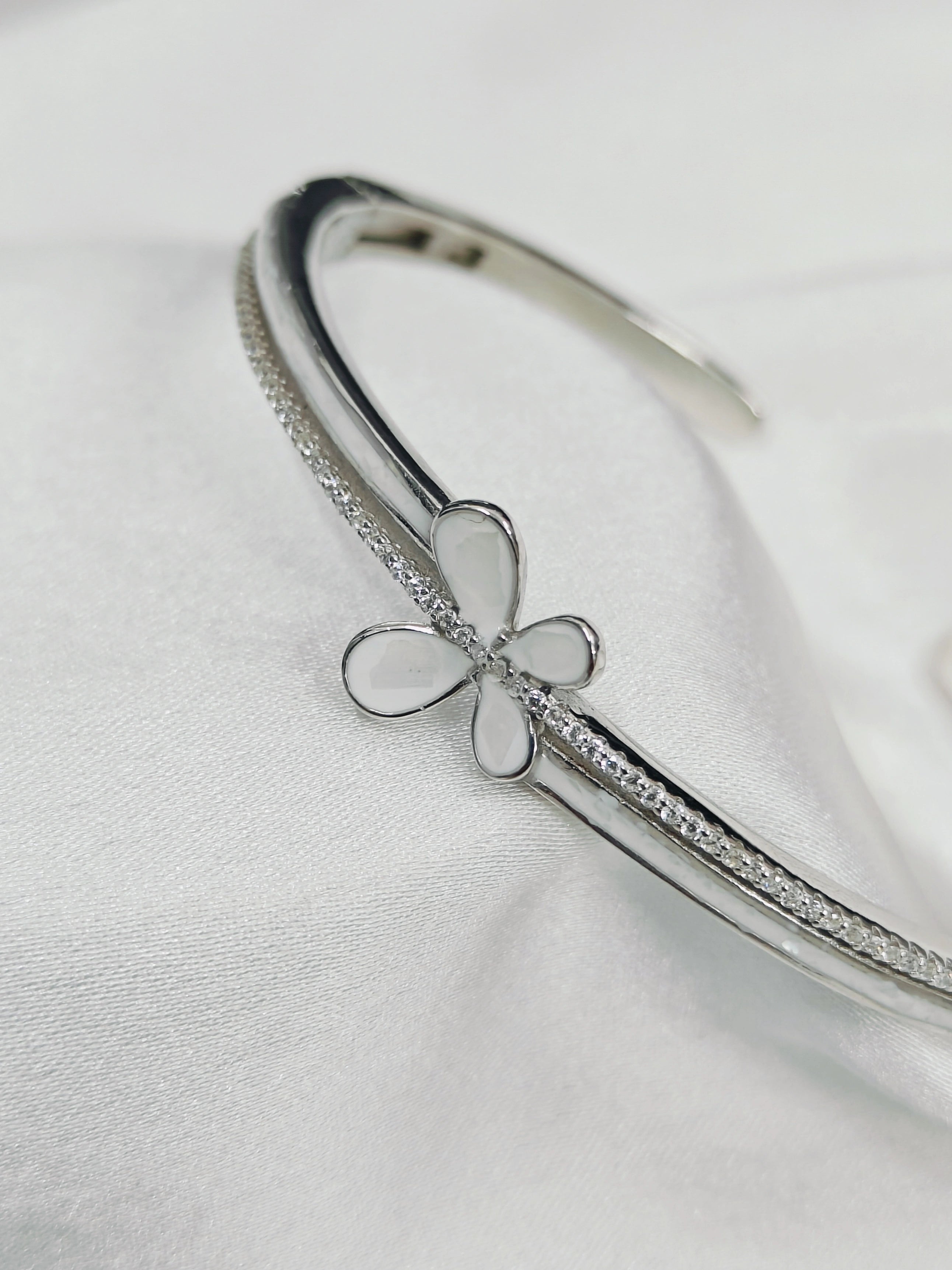 Silver bracelet with a butterfly charm on a light gray background