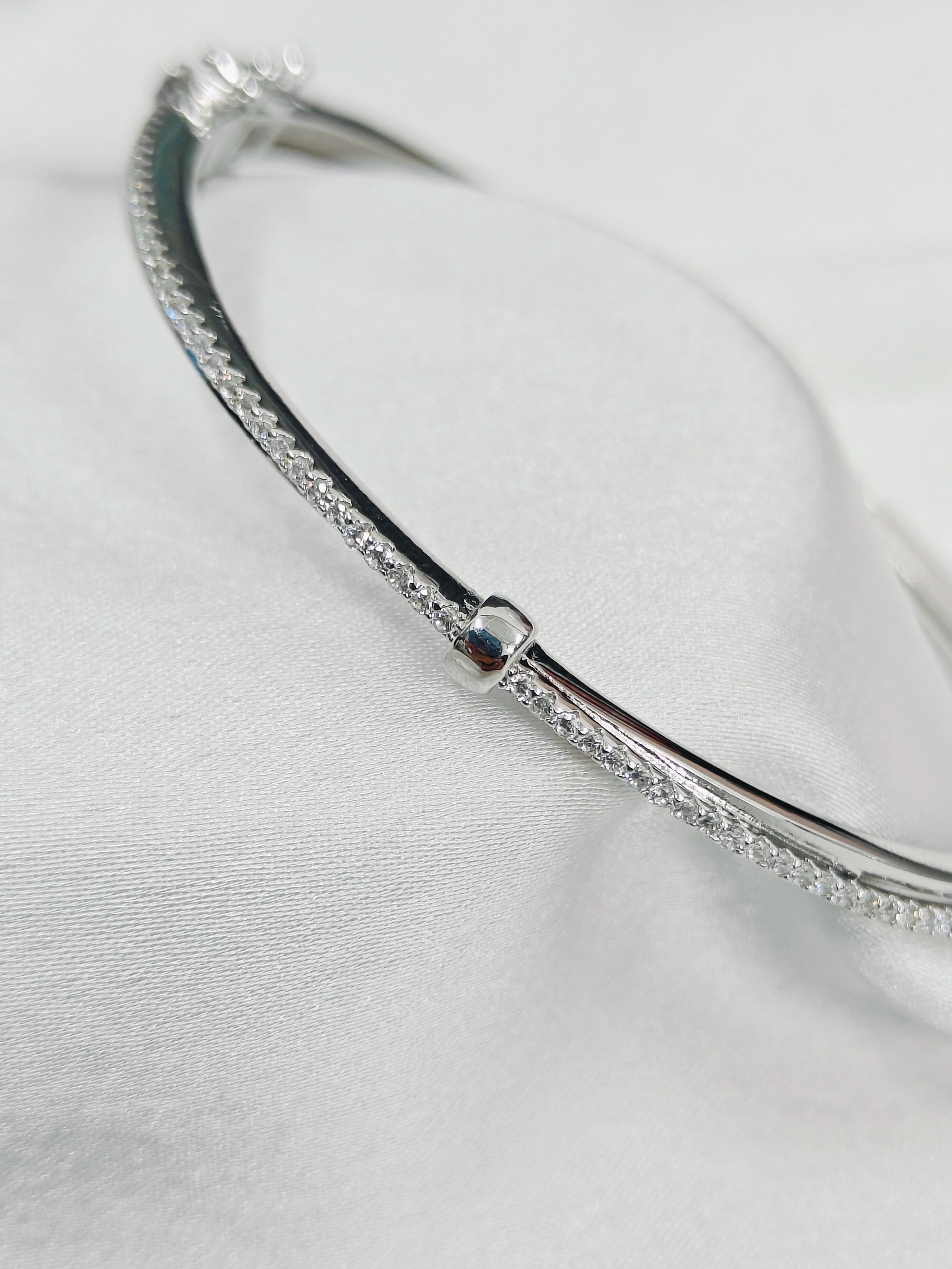 Silver bracelet with small stones on a light gray background