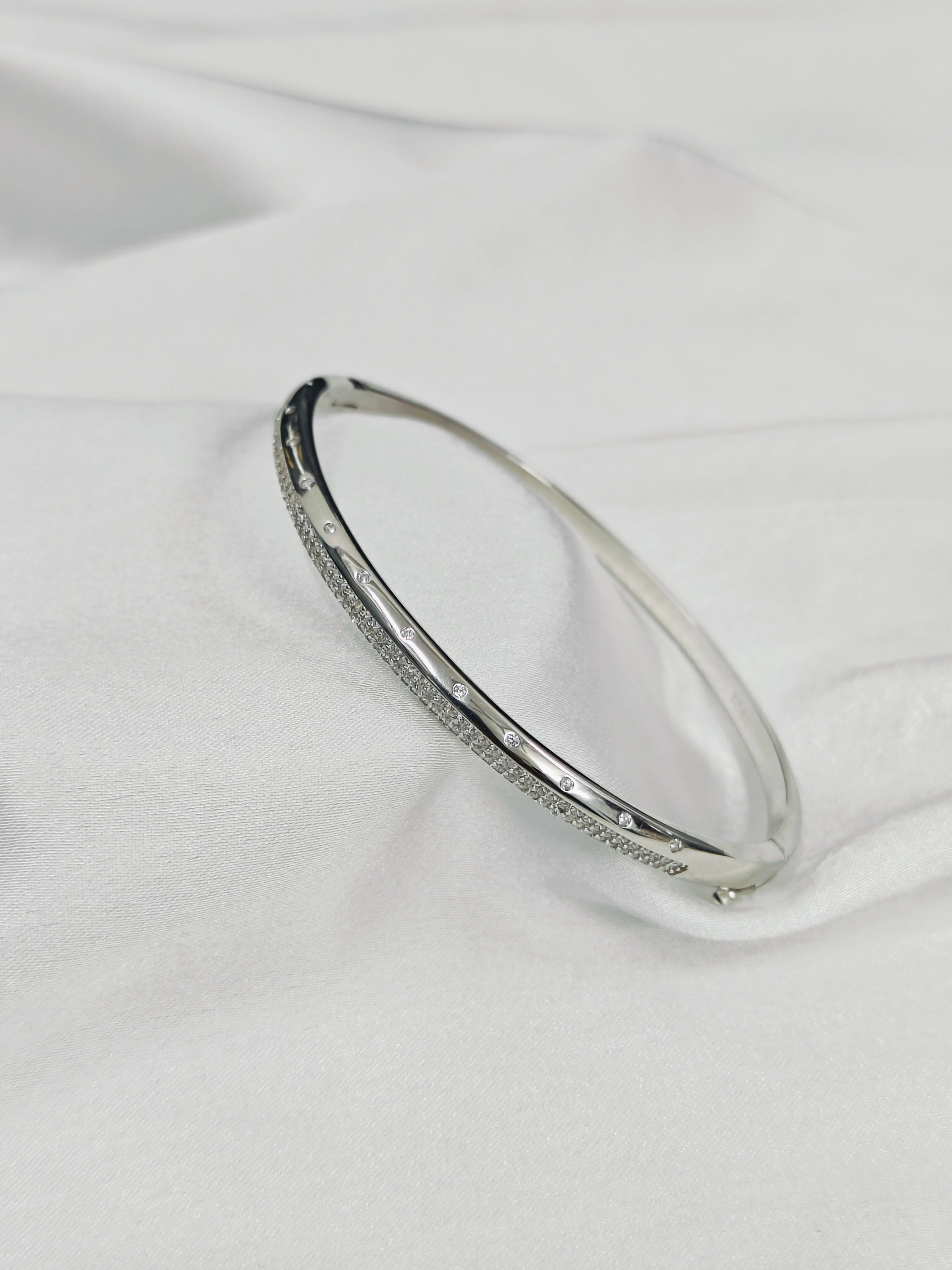 Silver bracelet with small stones on a white fabric background