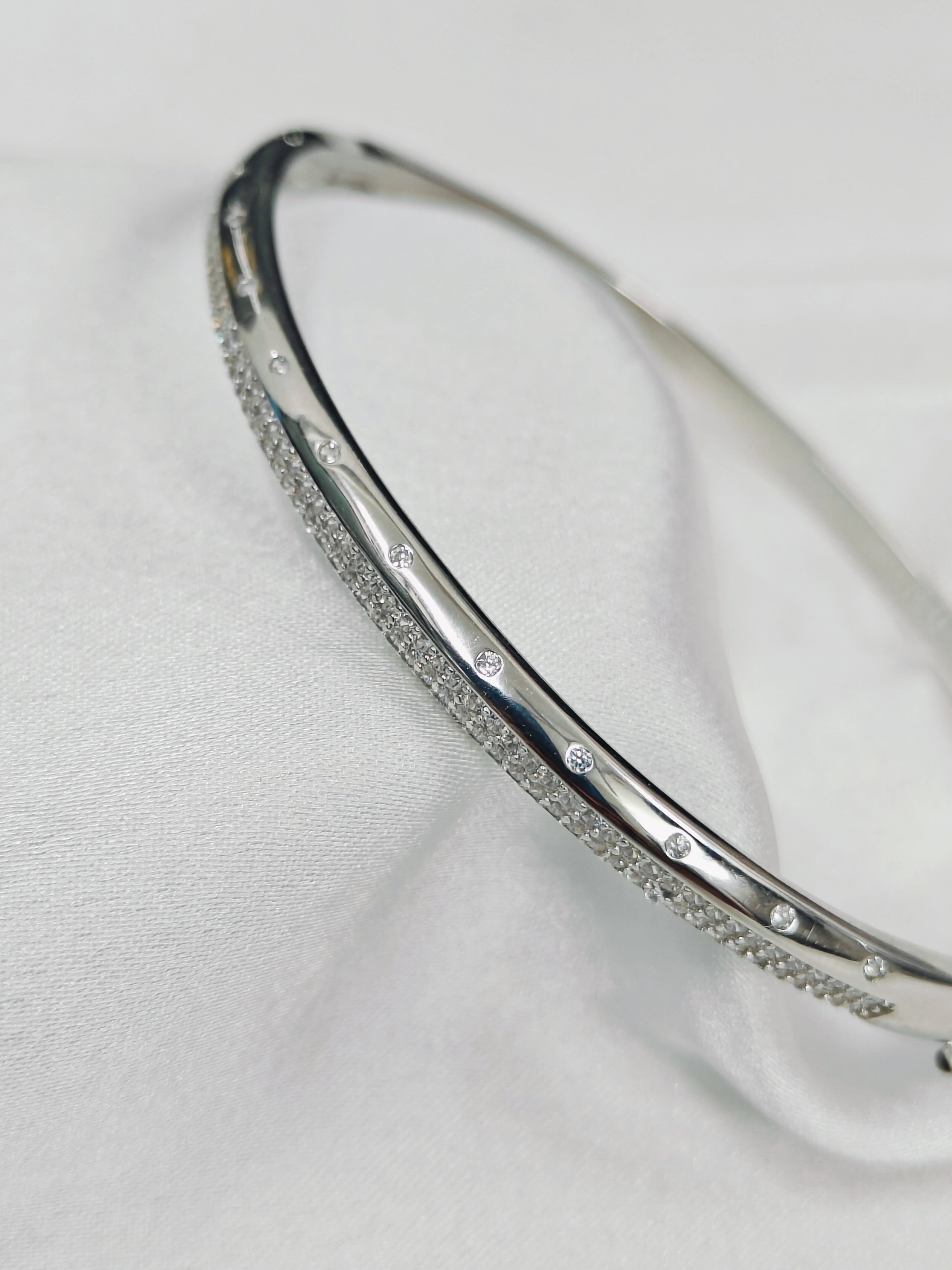 Silver bracelet with small stones on a light gray background