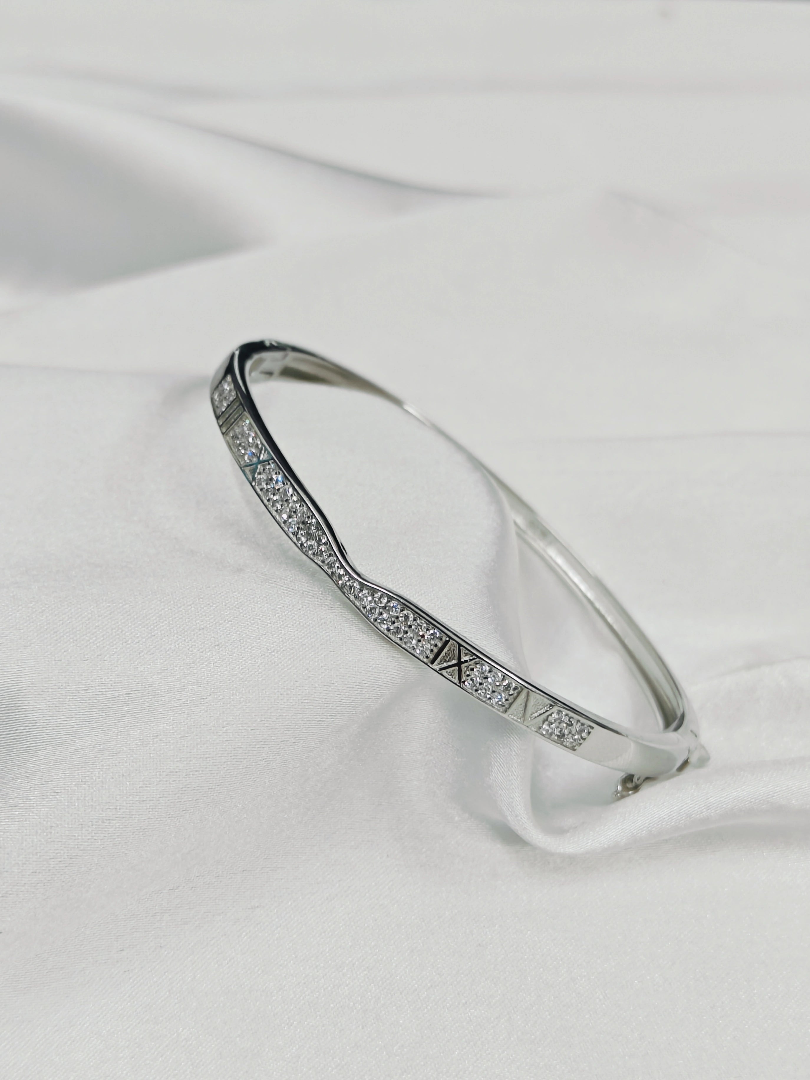 Silver bracelet with gemstones on a white fabric background