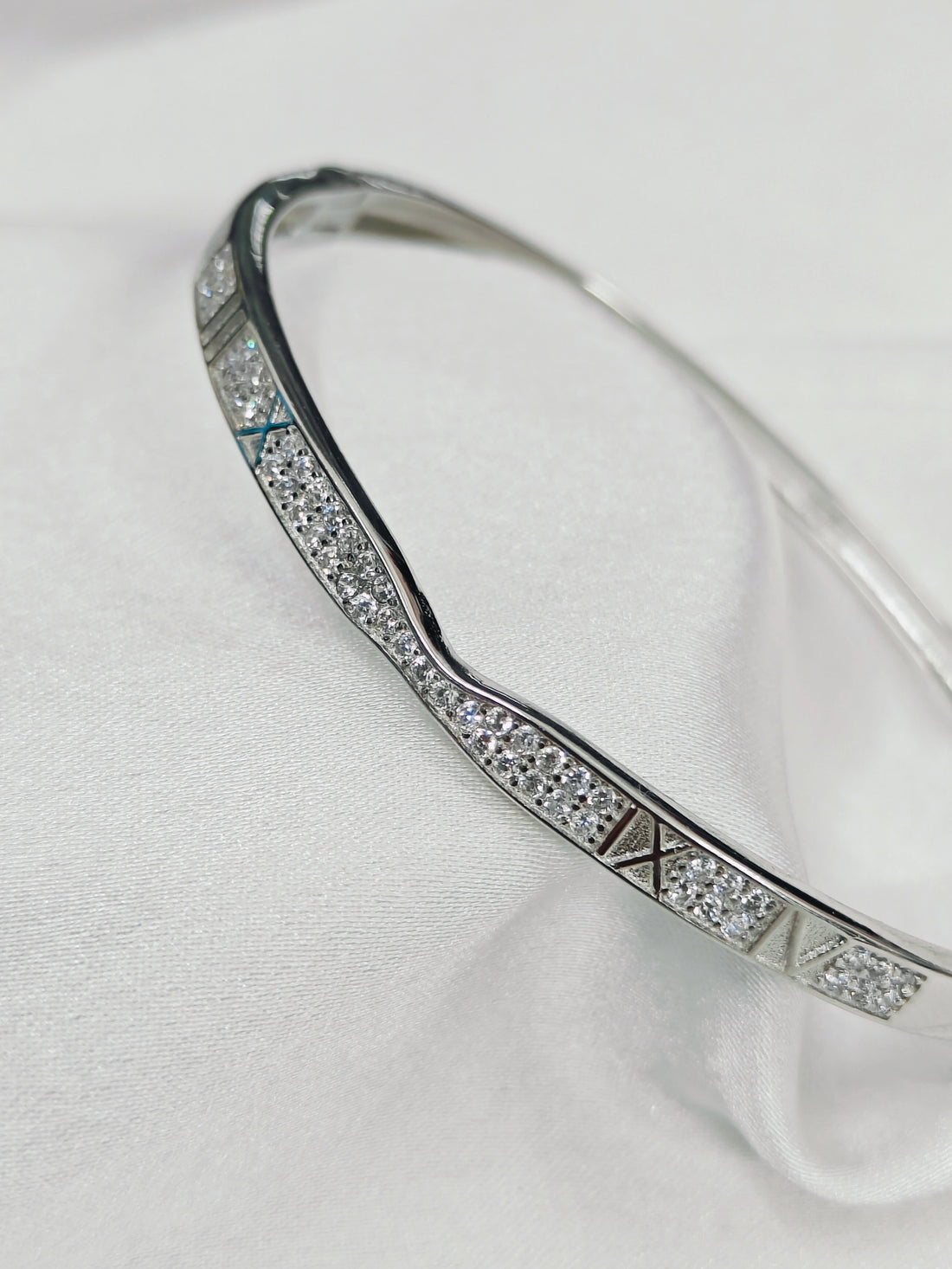 Silver bracelet with diamond accents on a white fabric background