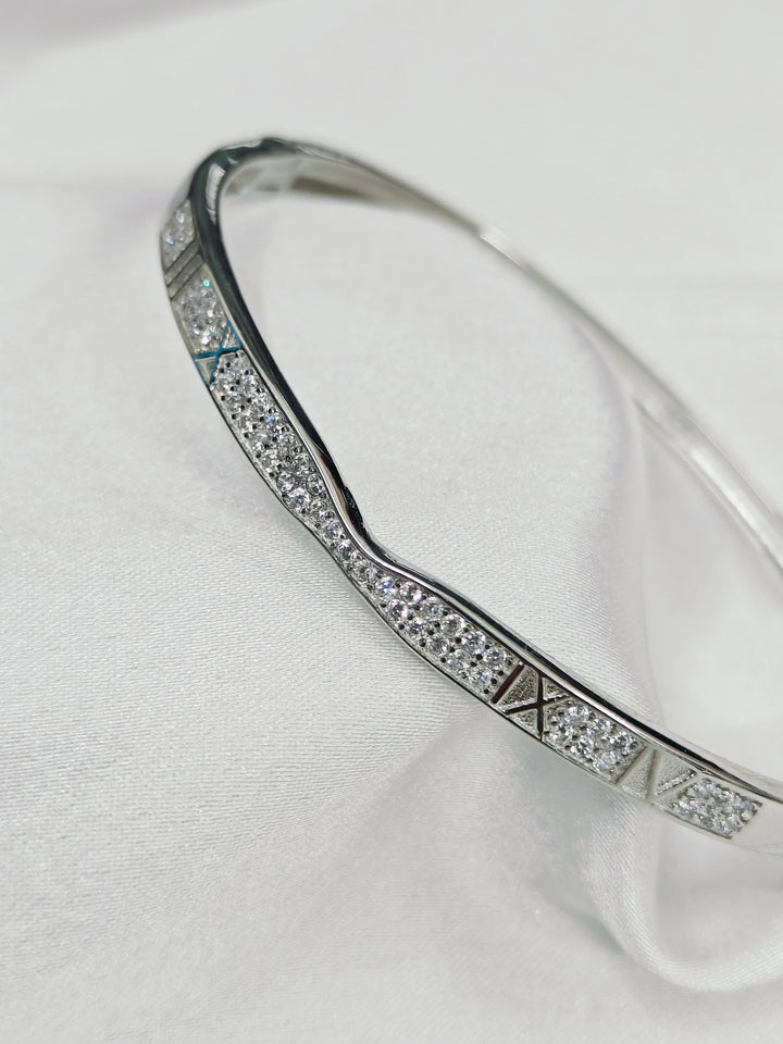 Silver bracelet with diamond accents on a white fabric background