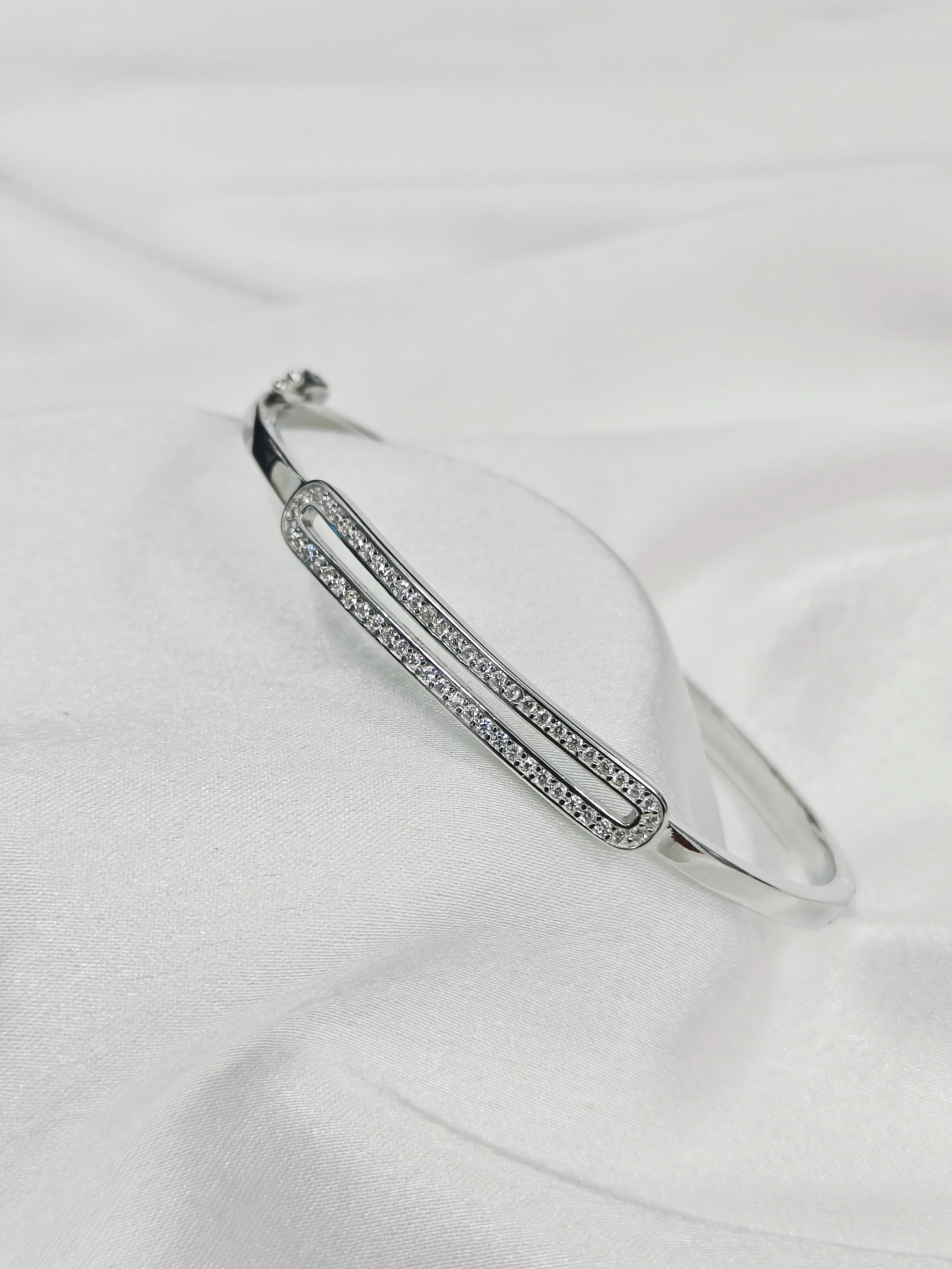 Silver bracelet with small stones on a white fabric background