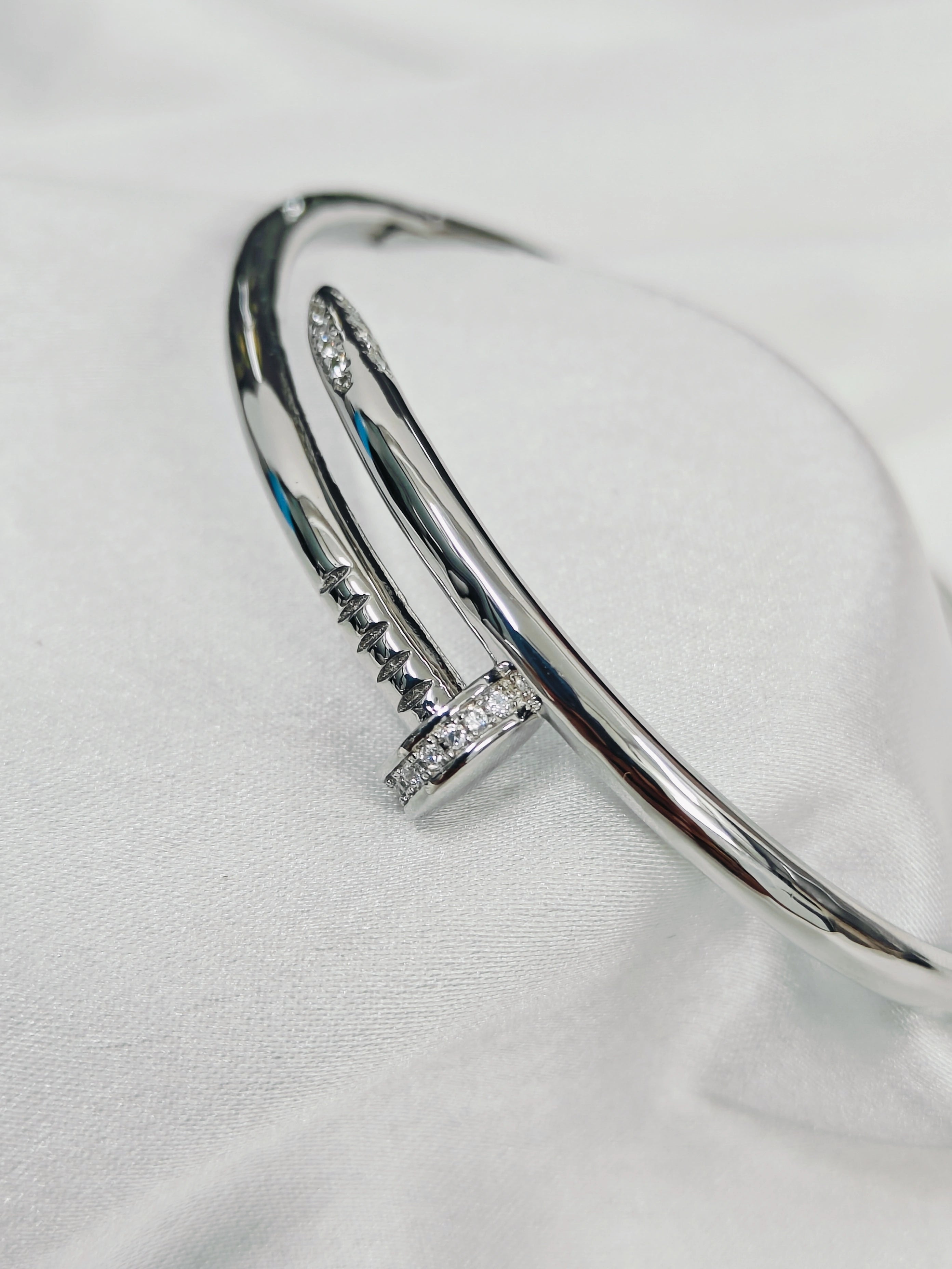 Silver bangle with embedded stones on a white fabric background