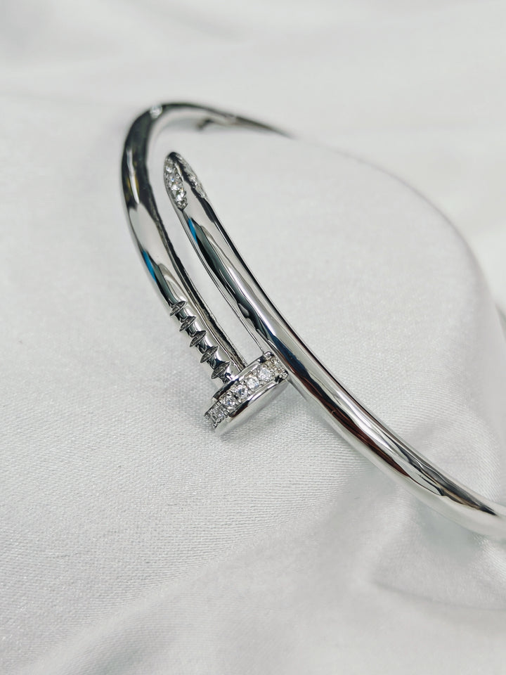 Silver bangle with embedded stones on a white fabric background