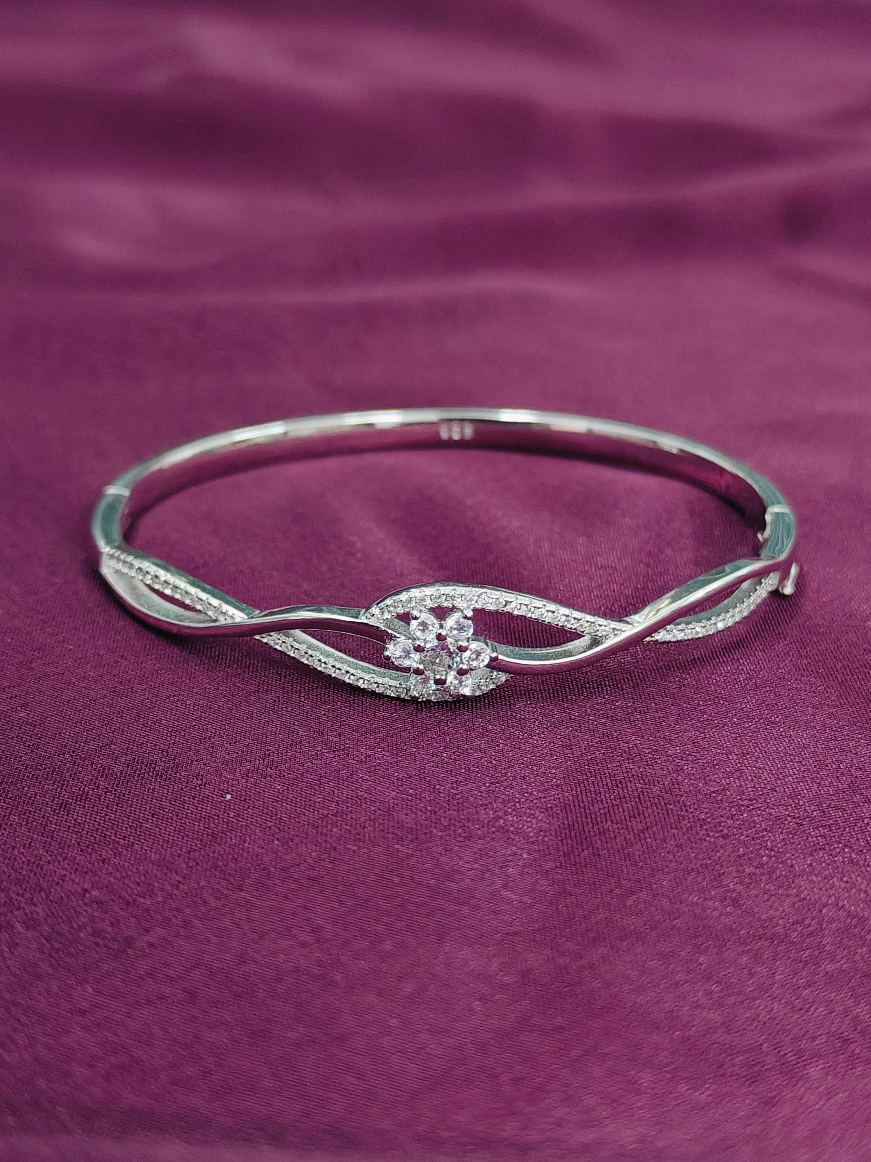 Silver bracelet with floral design on a purple fabric background