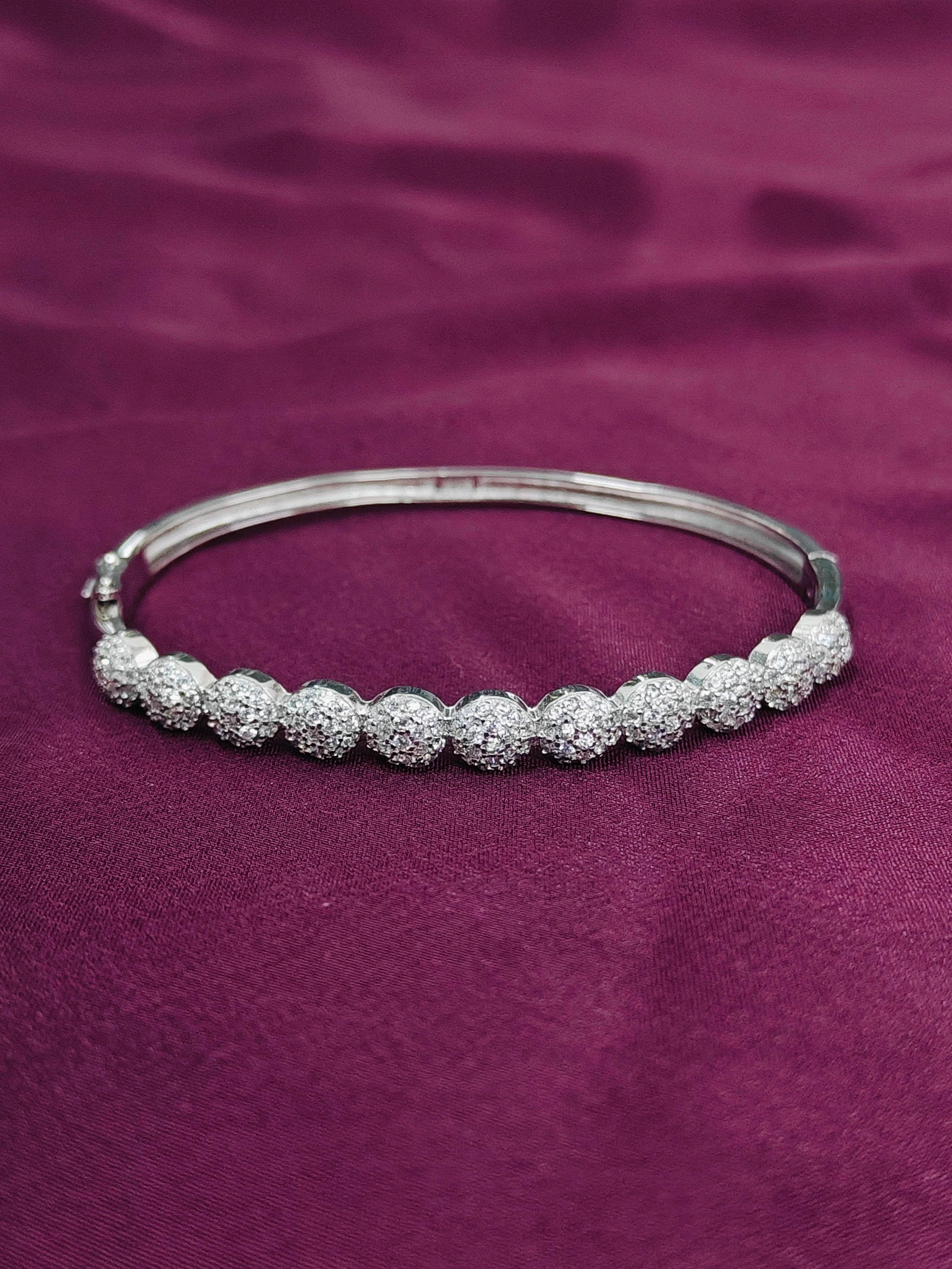 Silver bracelet with beaded design on a purple fabric background