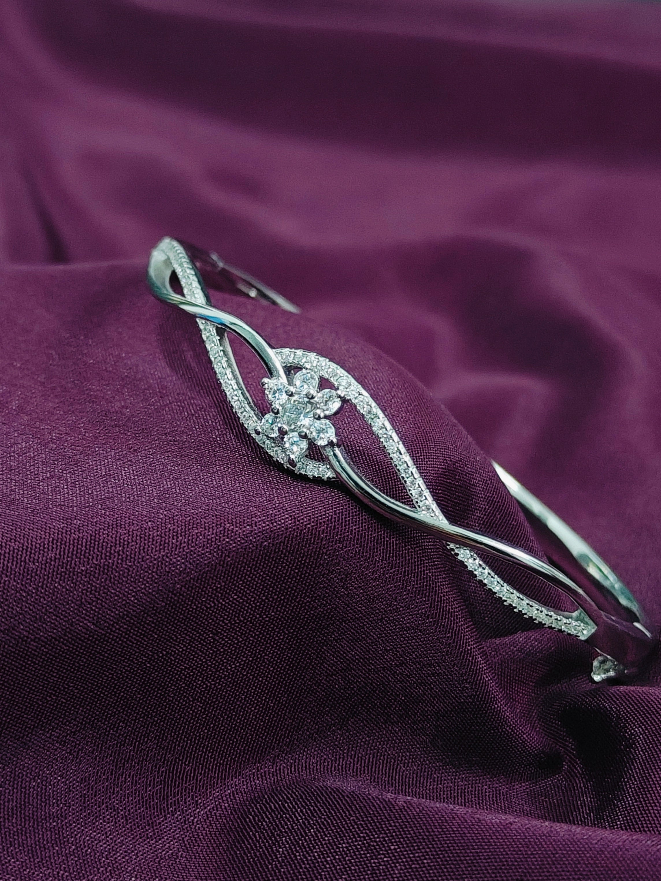 Silver hair clip with floral design on a purple fabric background