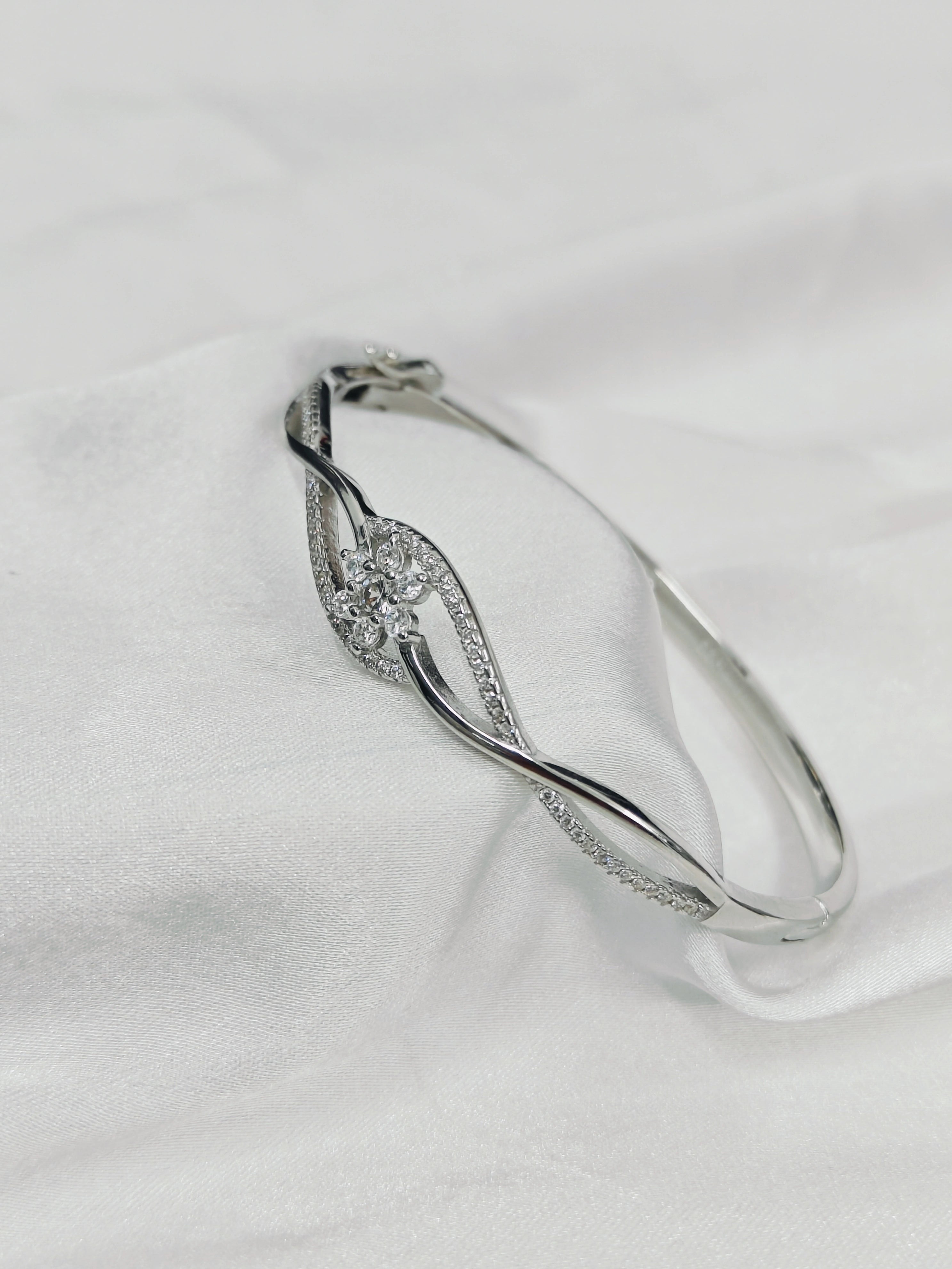 Silver bracelet with gemstones on a white fabric background