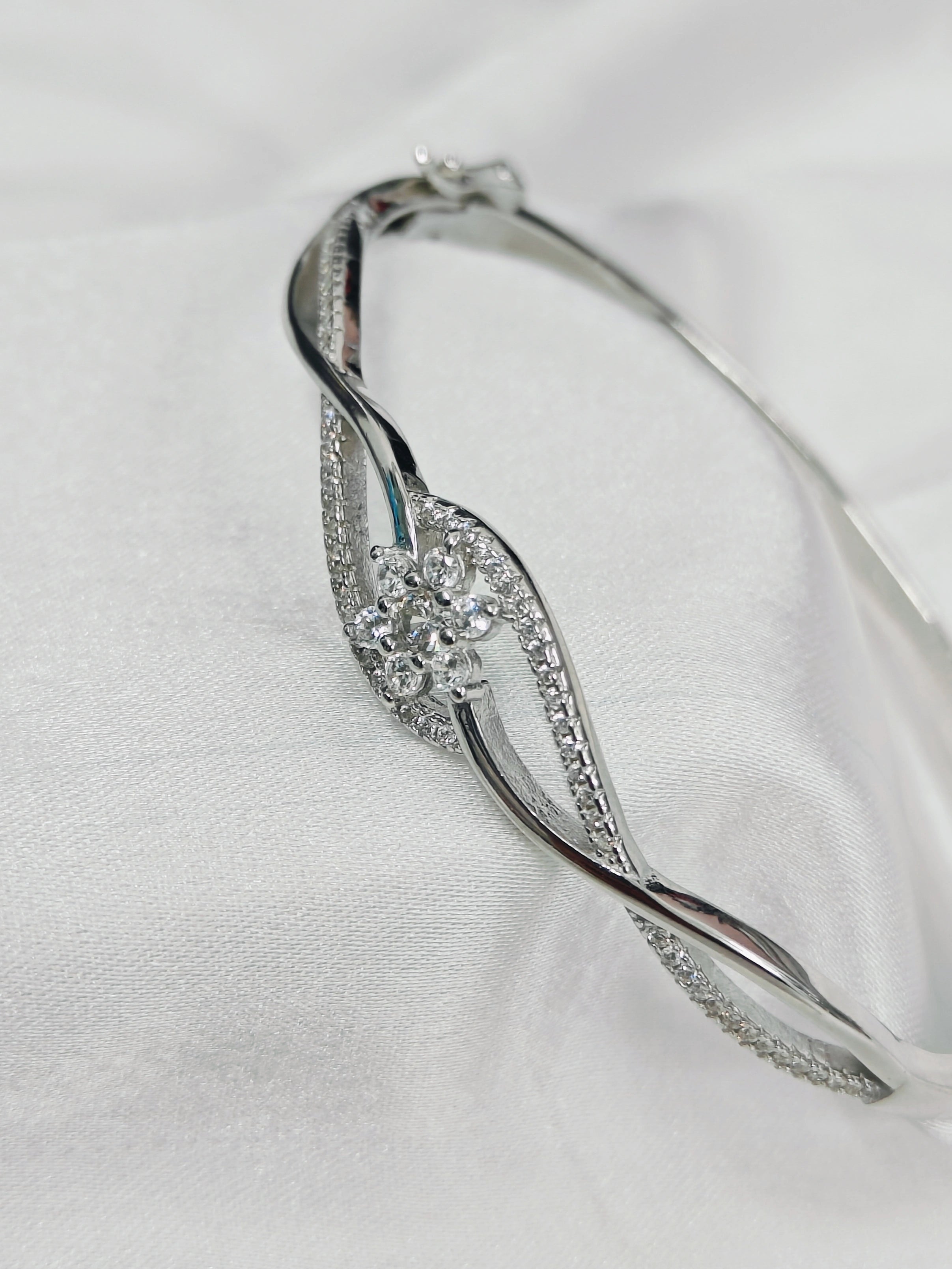 Silver bracelet with floral design on a white fabric background