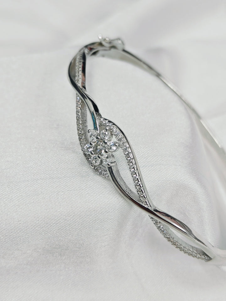 Silver bracelet with floral design on a white fabric background