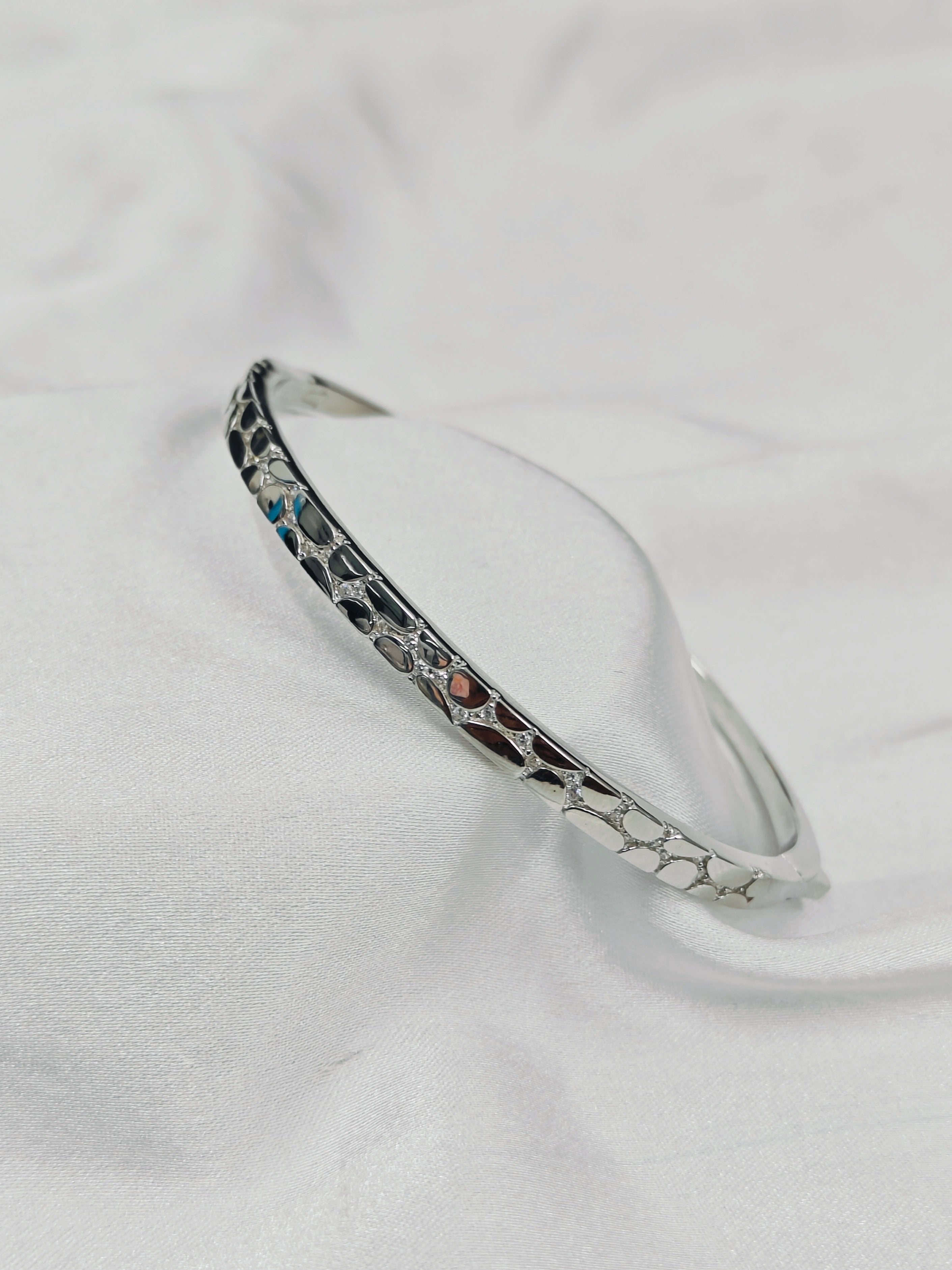 Silver bracelet with marbled design on a white background