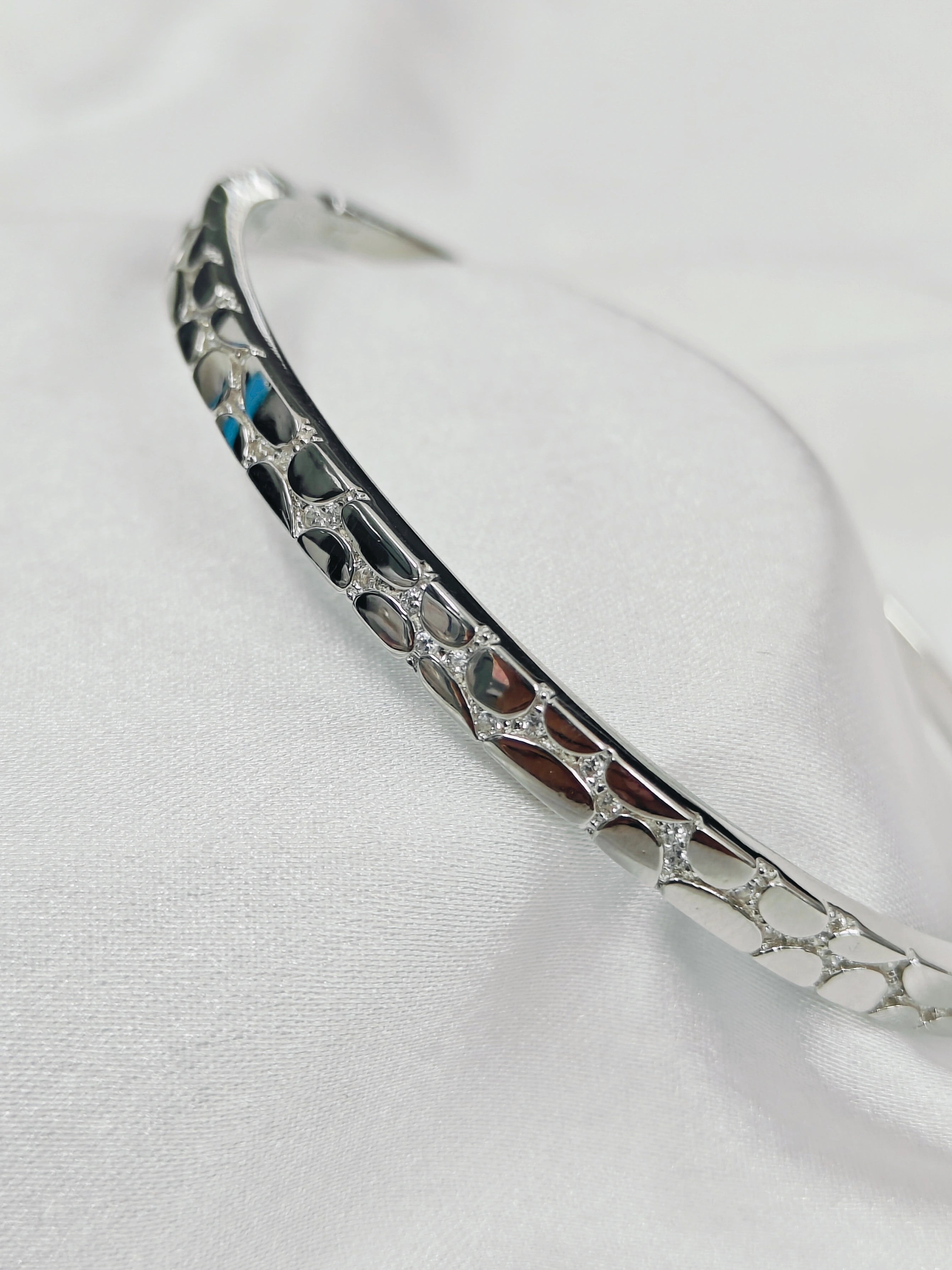 Silver bracelet with intricate design on a white background