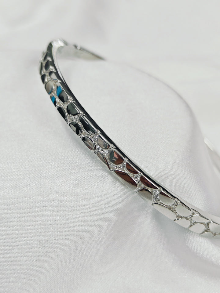 Silver bracelet with intricate design on a white background