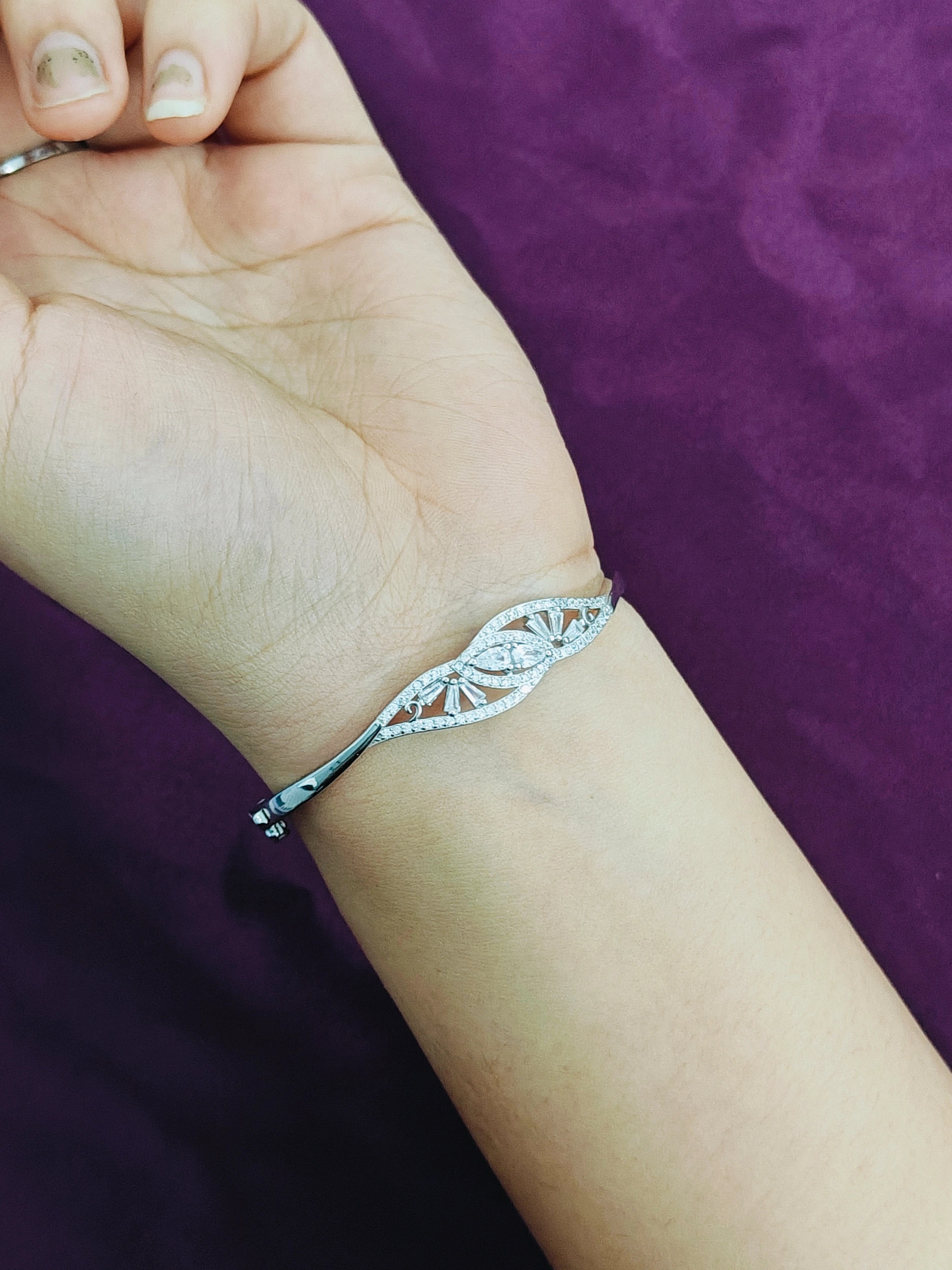 Silver bracelet on a wrist with a purple background