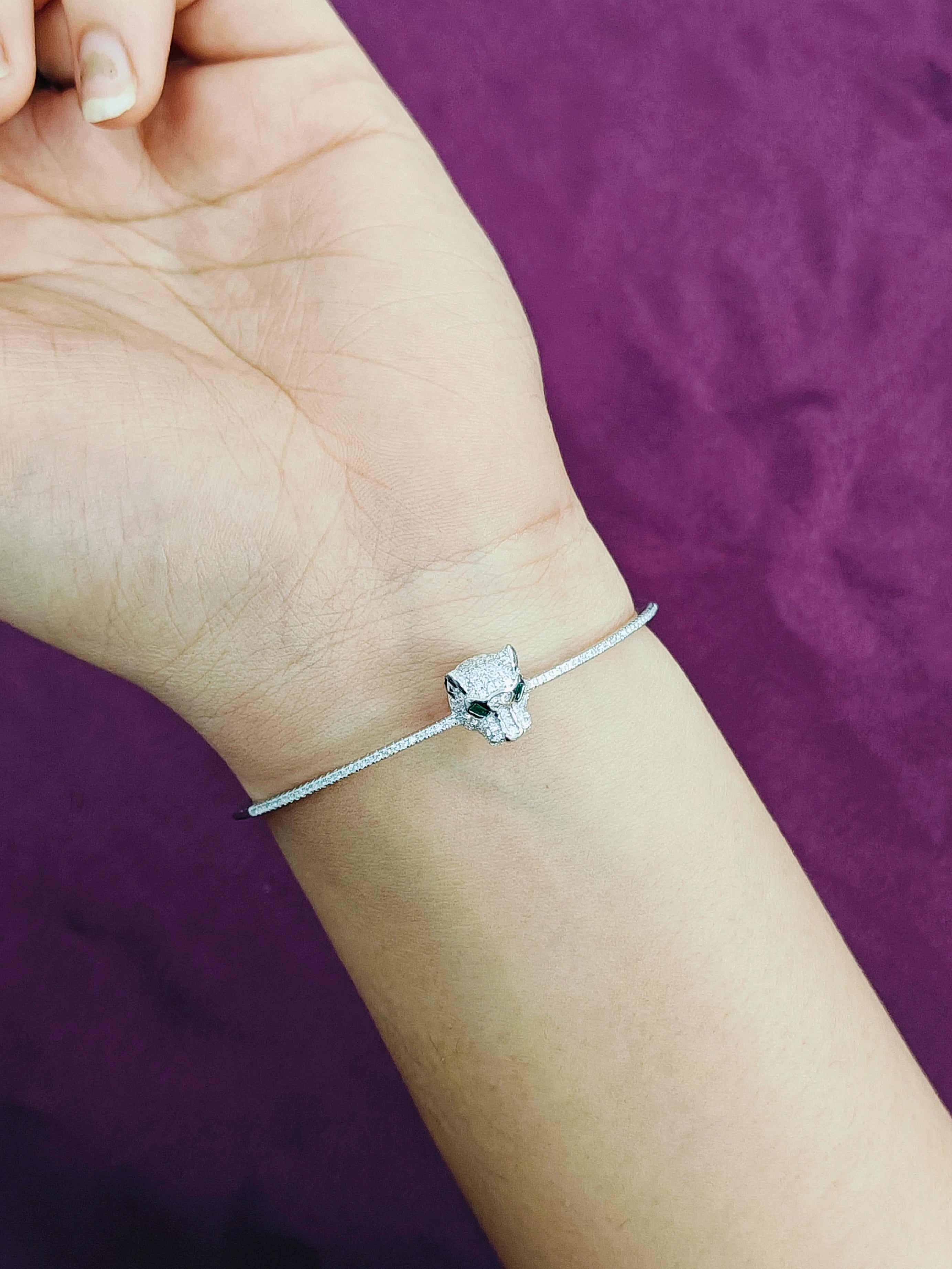 Silver bracelet with a diamond on a wrist against a purple background