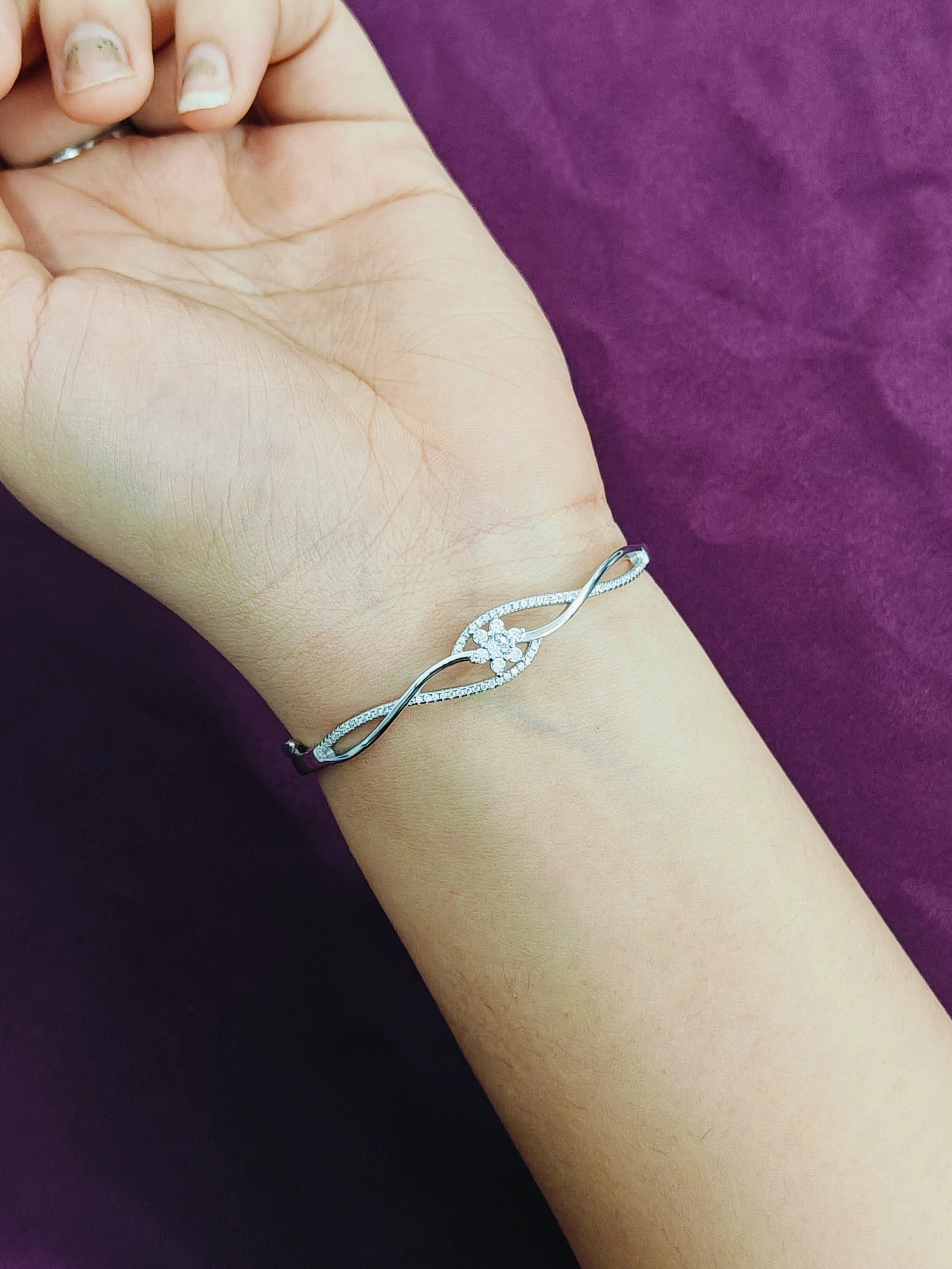 Silver bracelet on a wrist against a purple background
