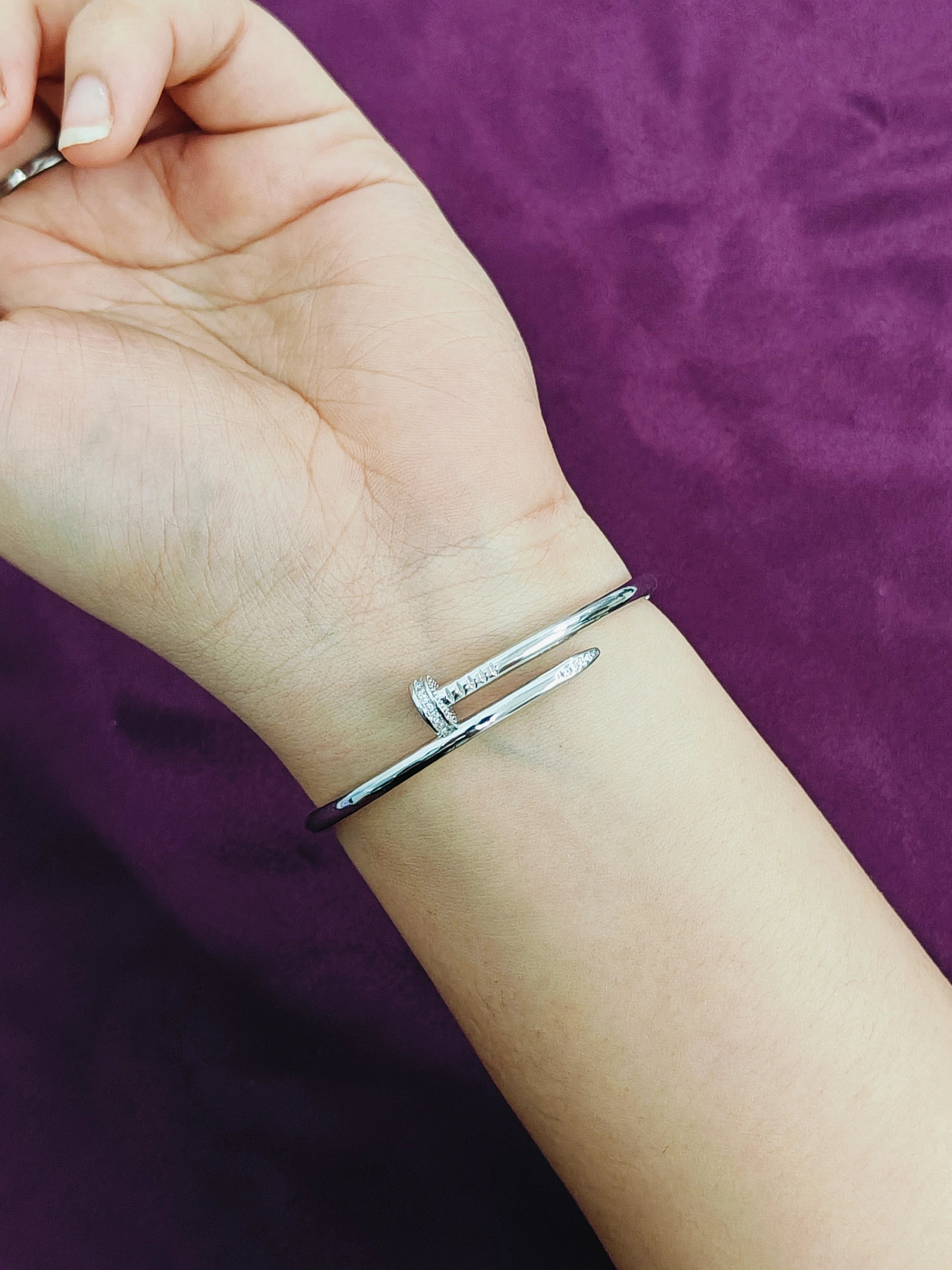Silver bracelet on a wrist with a purple background