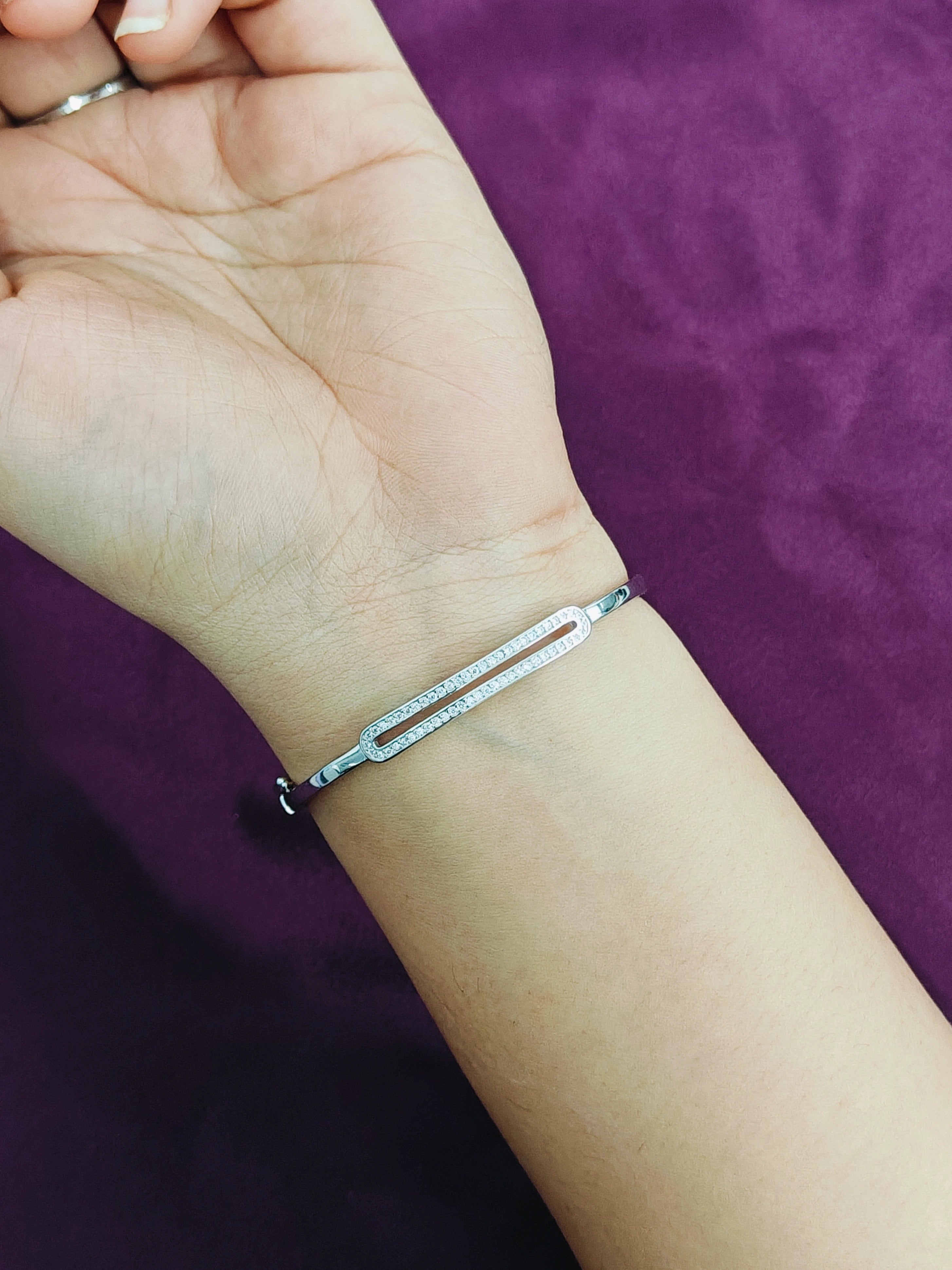 Silver bracelet on a wrist against a purple background